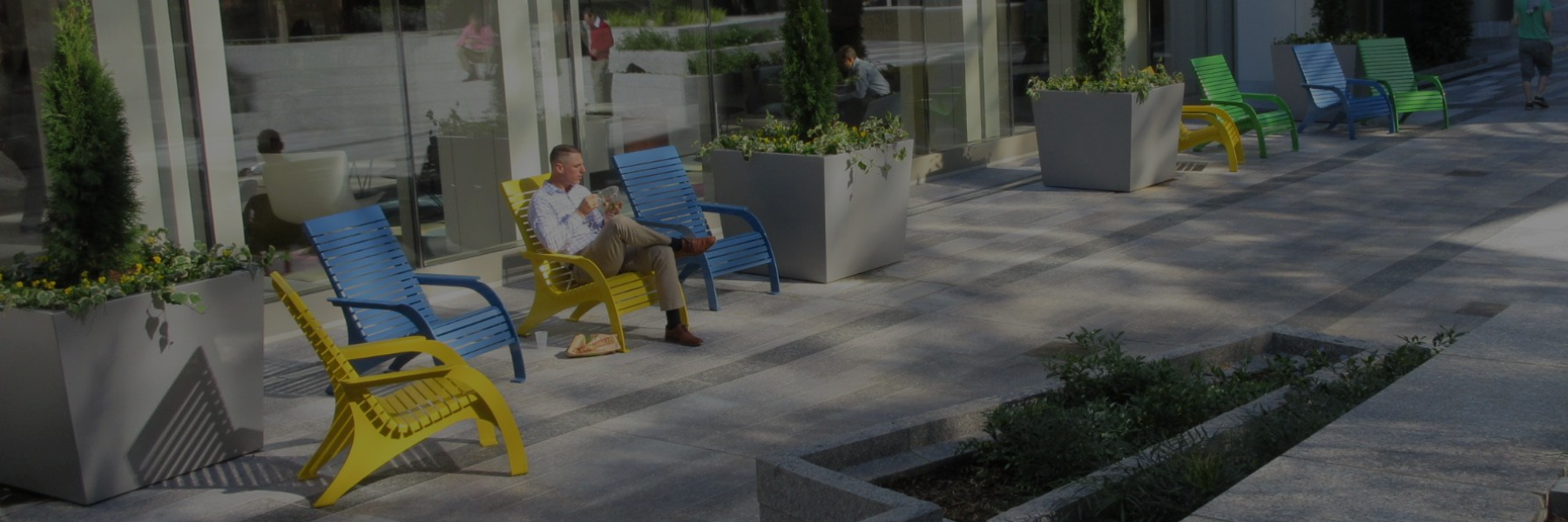 Man sitting in Adirondack type chair outside an office building 
