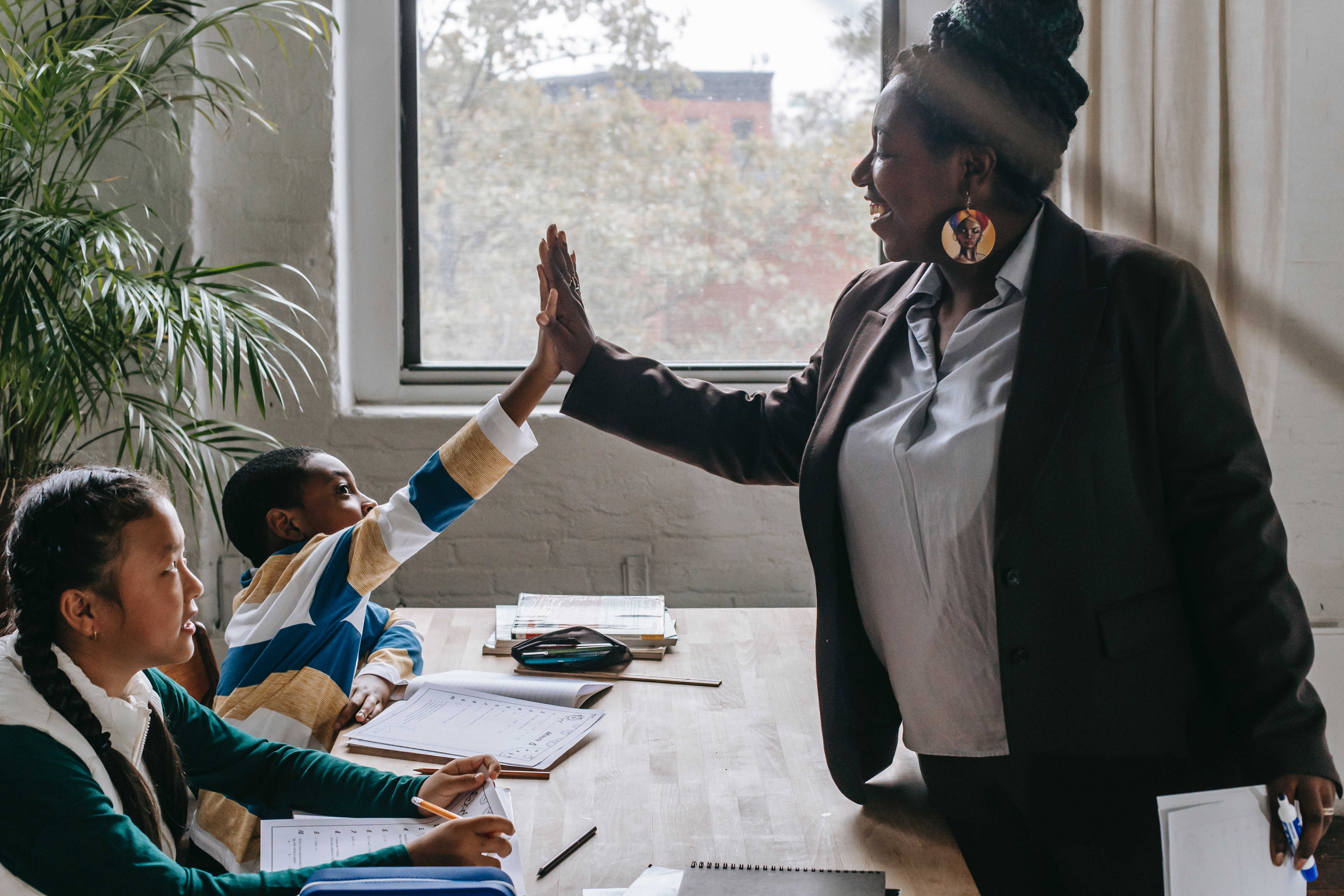 teacher high-fiving students at a desk