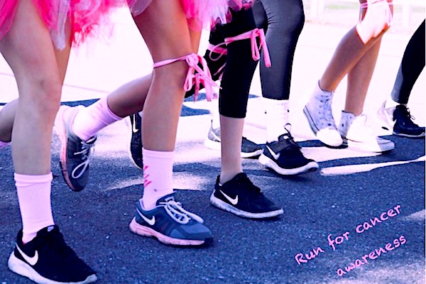 Runners wearing pink ribbons line up at the start line for a run in aid of cancer awareness