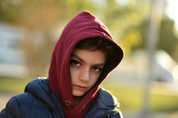 teenage boy in hooded sweatshirt looking forlorn