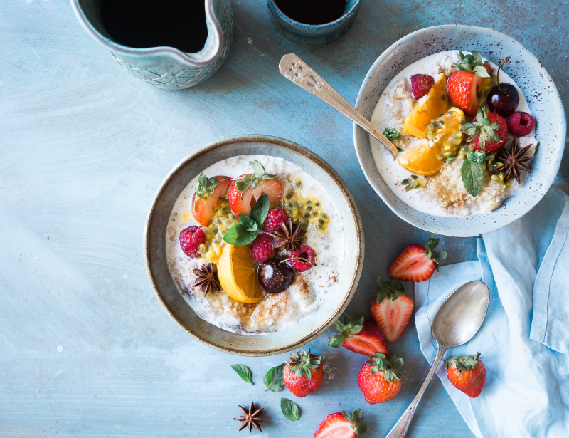 Dos bowls de avena con leche cubiertos de frutas variadas.