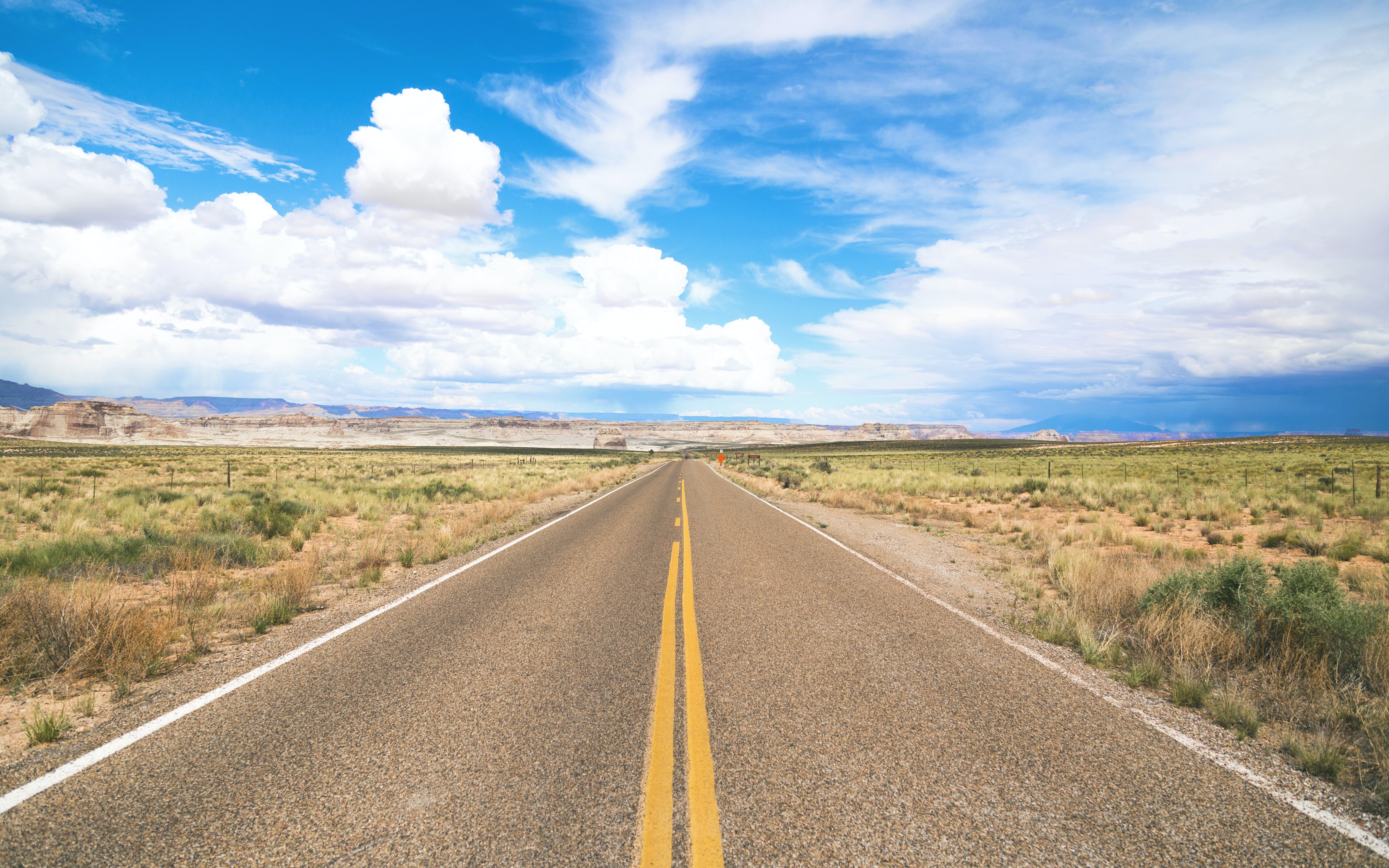 Photo of a cloudy sky with an empty two lane road // Copyright to original photographer