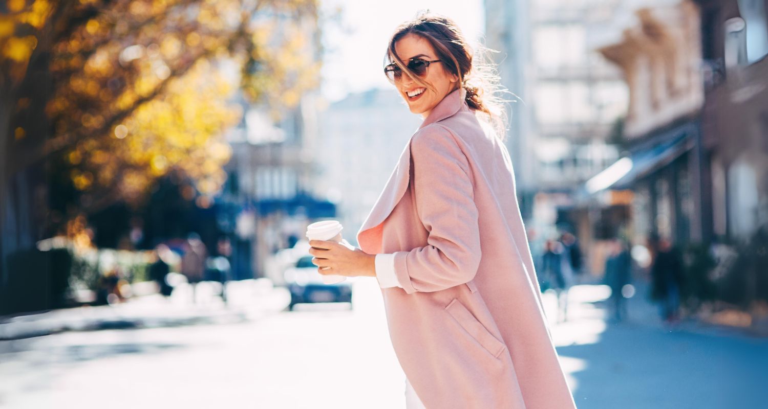 Smiling elegant woman wearing pink coat and sunglasses