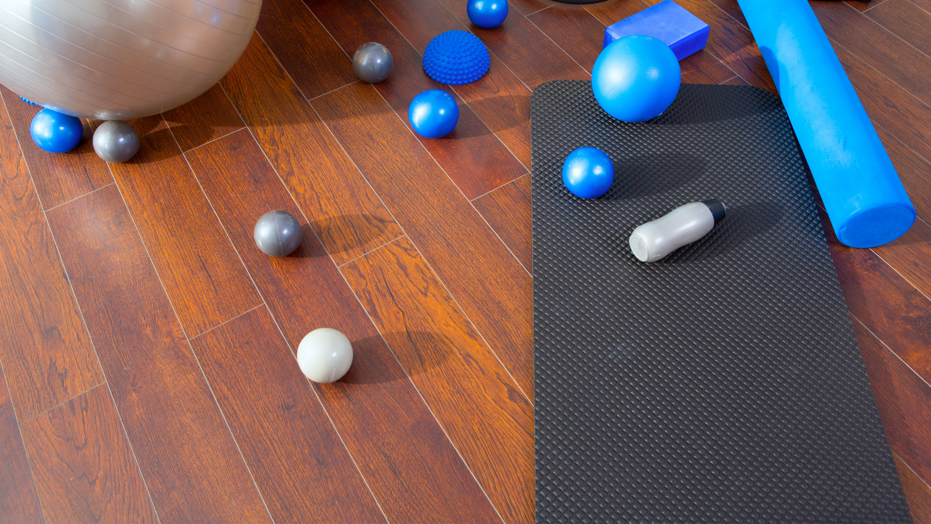 A yoga mat, foam roller and different sized sport balls.