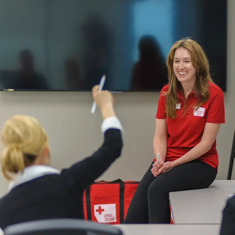 A participant in a class led by a Canadian Red Cross instructor raises her hand.