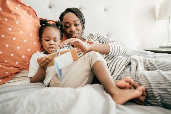 Mother and daughter cozy in bed reading a book