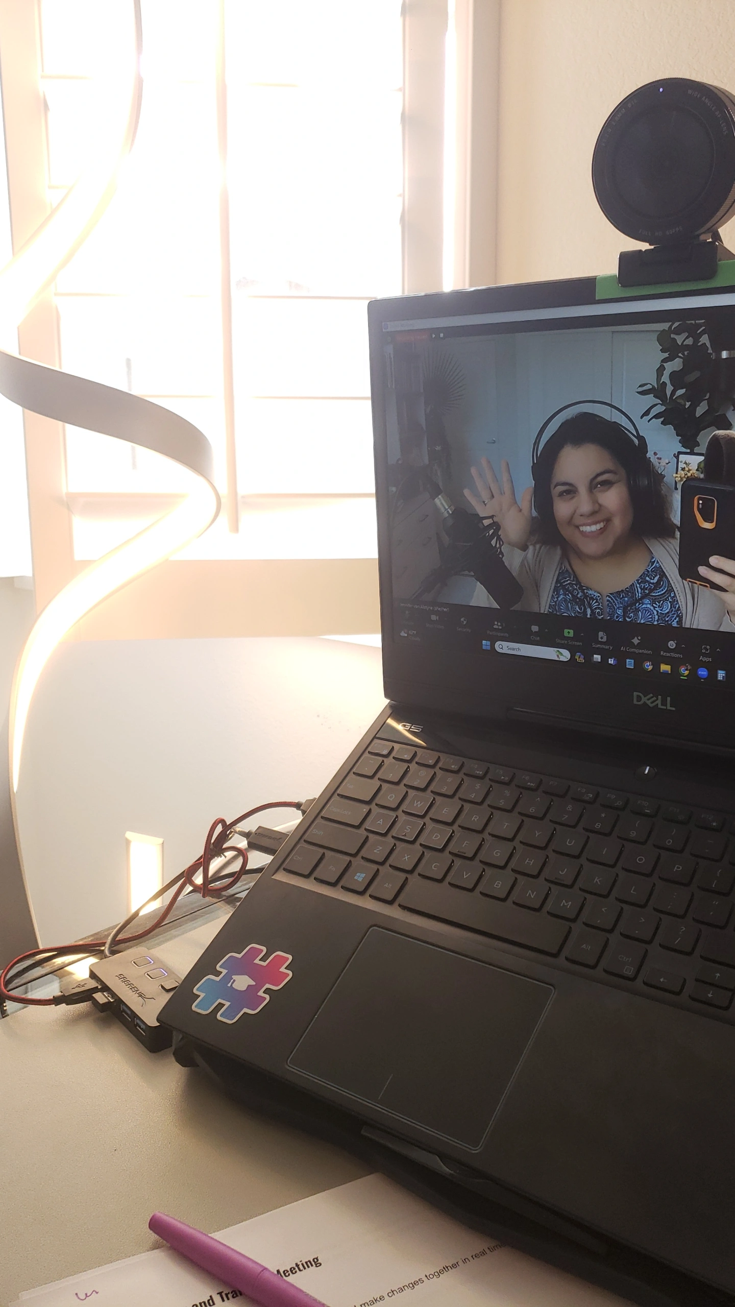 Jennifer on a Zoom screen on an open laptop, waving.