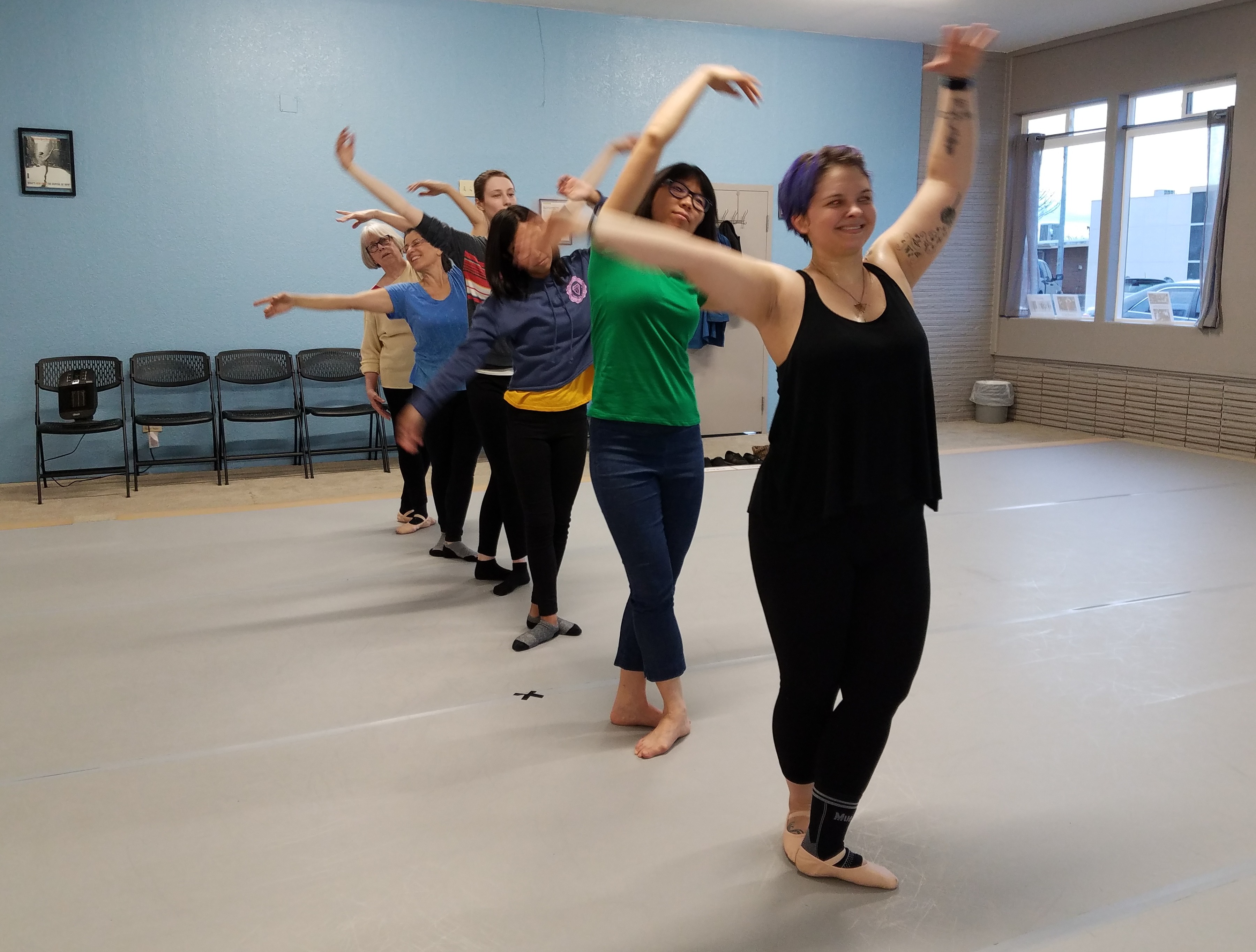 At Find Your Center&#39;s studio in 2019, six adult women of various shapes, sizes and ages stand in ballet positions in a line and sway their arms, looking at each other and smiling