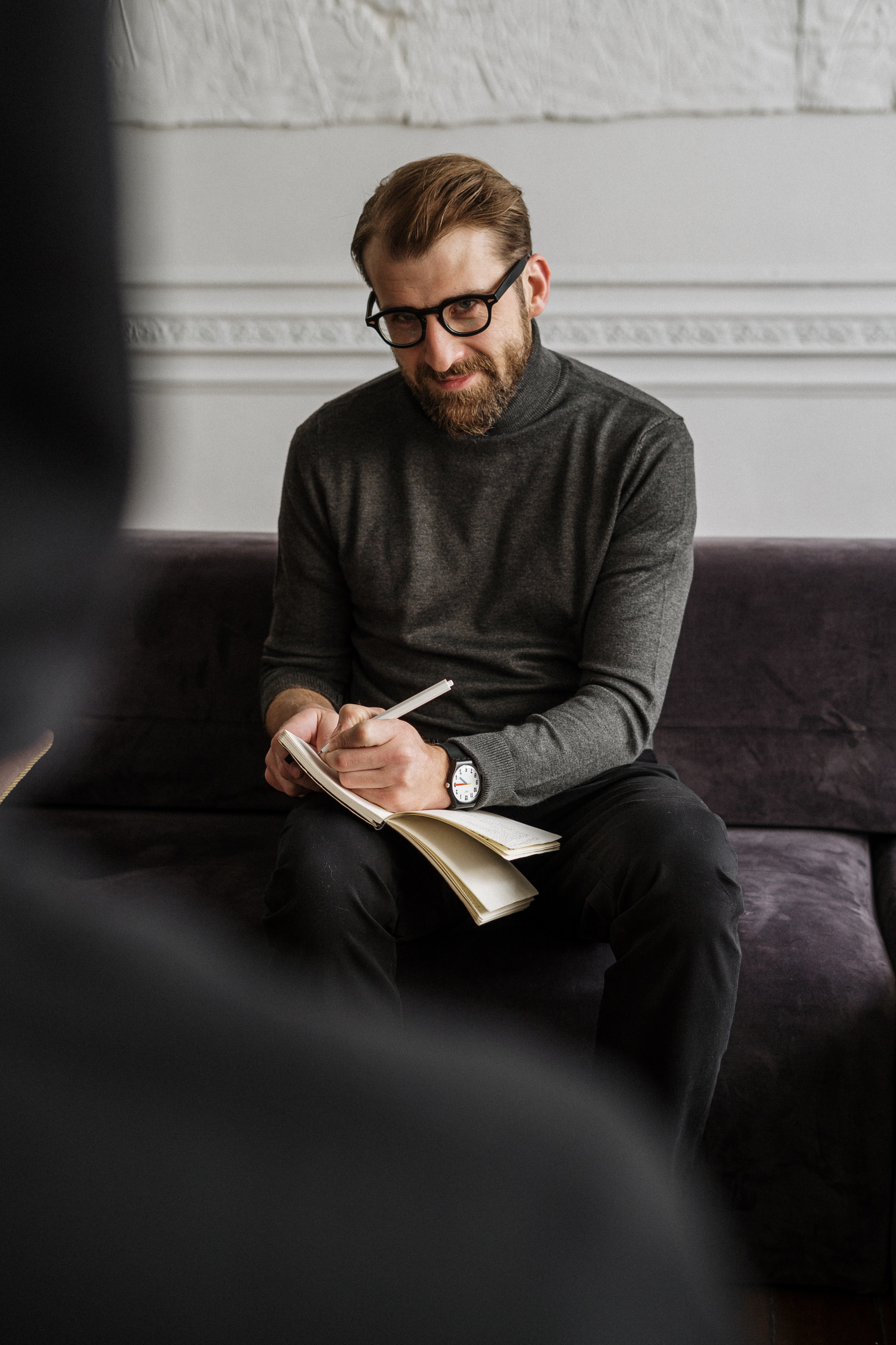 A Life Coach takes notes on a paper as he intently listens to the needs of his client.