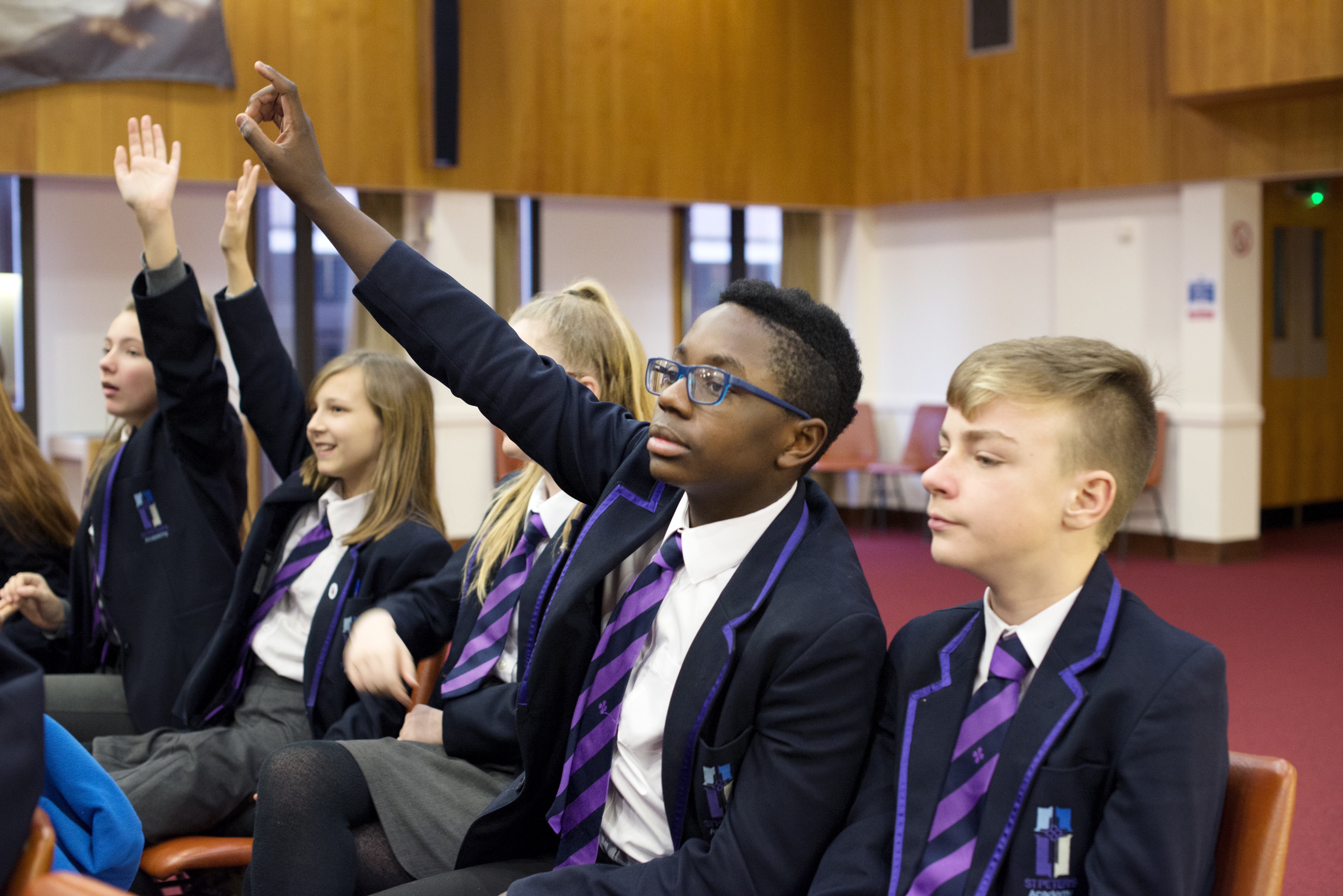 Key Stage 4 pupils raising their hands to answer questions