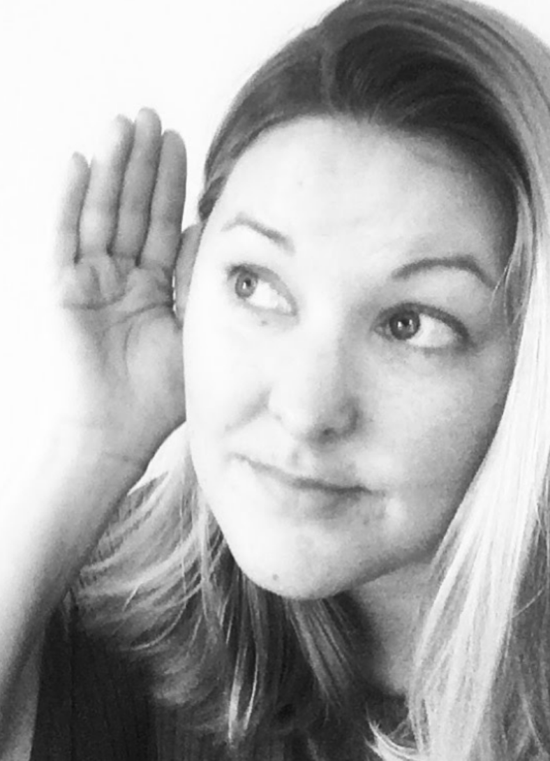 A black and white photo of me with my hand up to my ear listening.