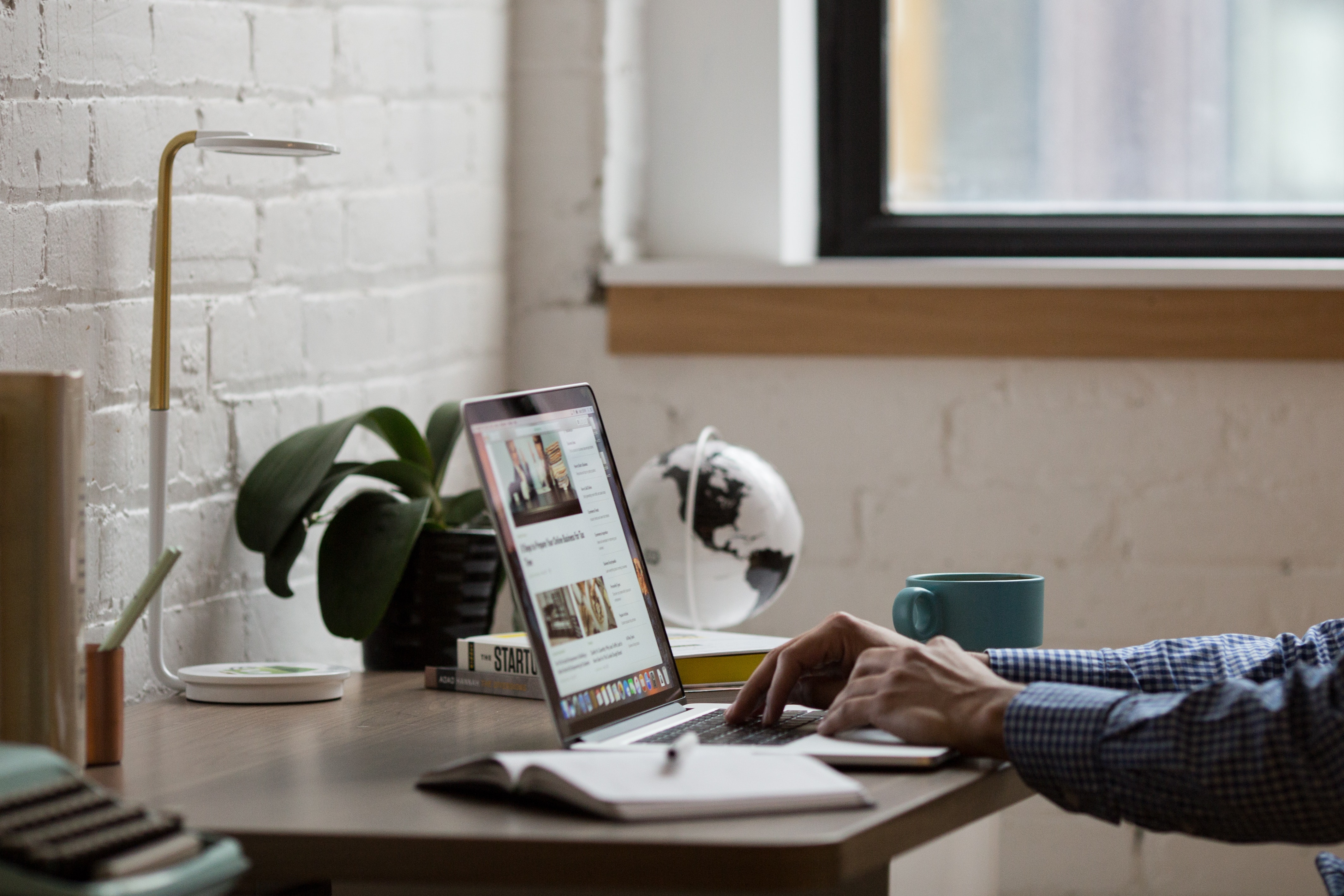 person typing on laptop keyboard on desk