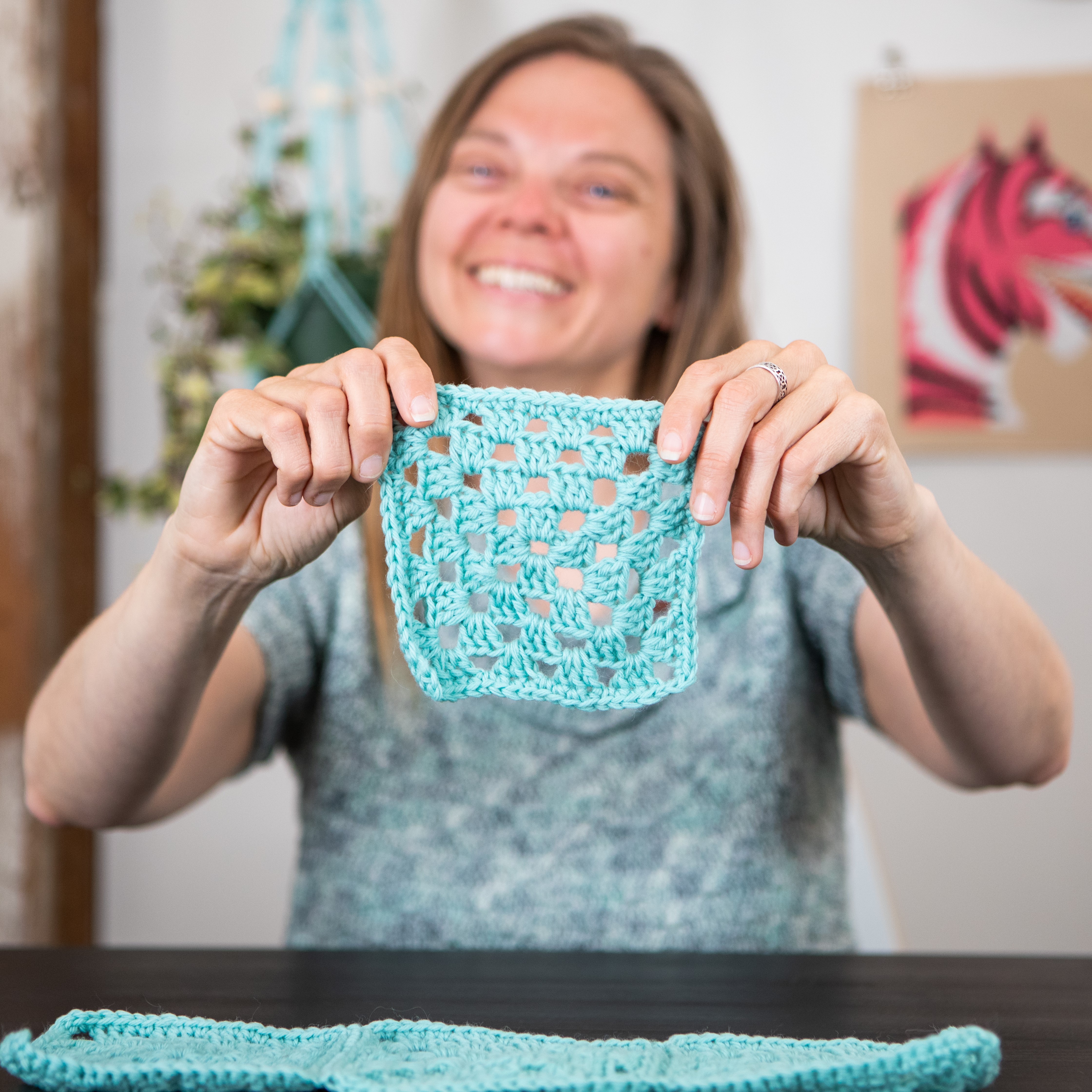 Dorian holding a granny square up to the camera