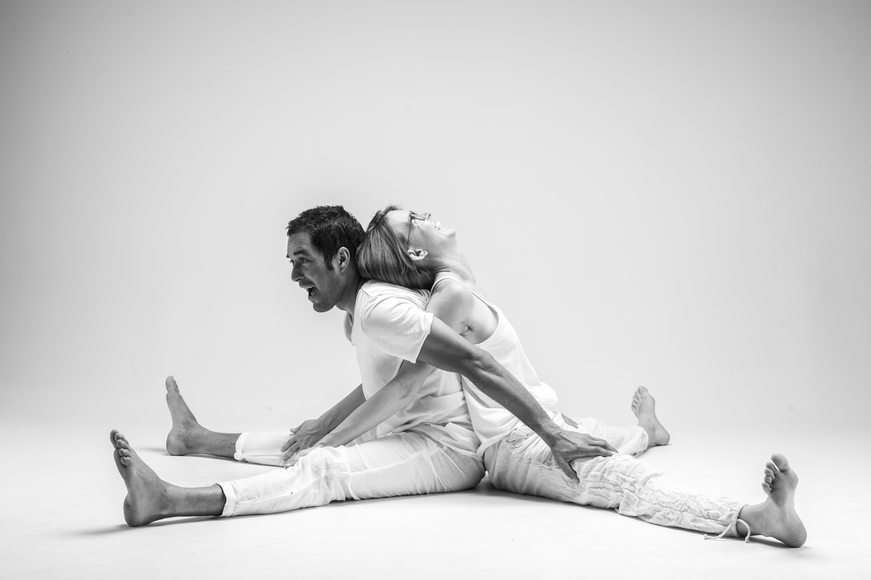 black and white image of yin yoga teachers Krishna and Kimberly Ghorai demonstrating straddle pose back to back