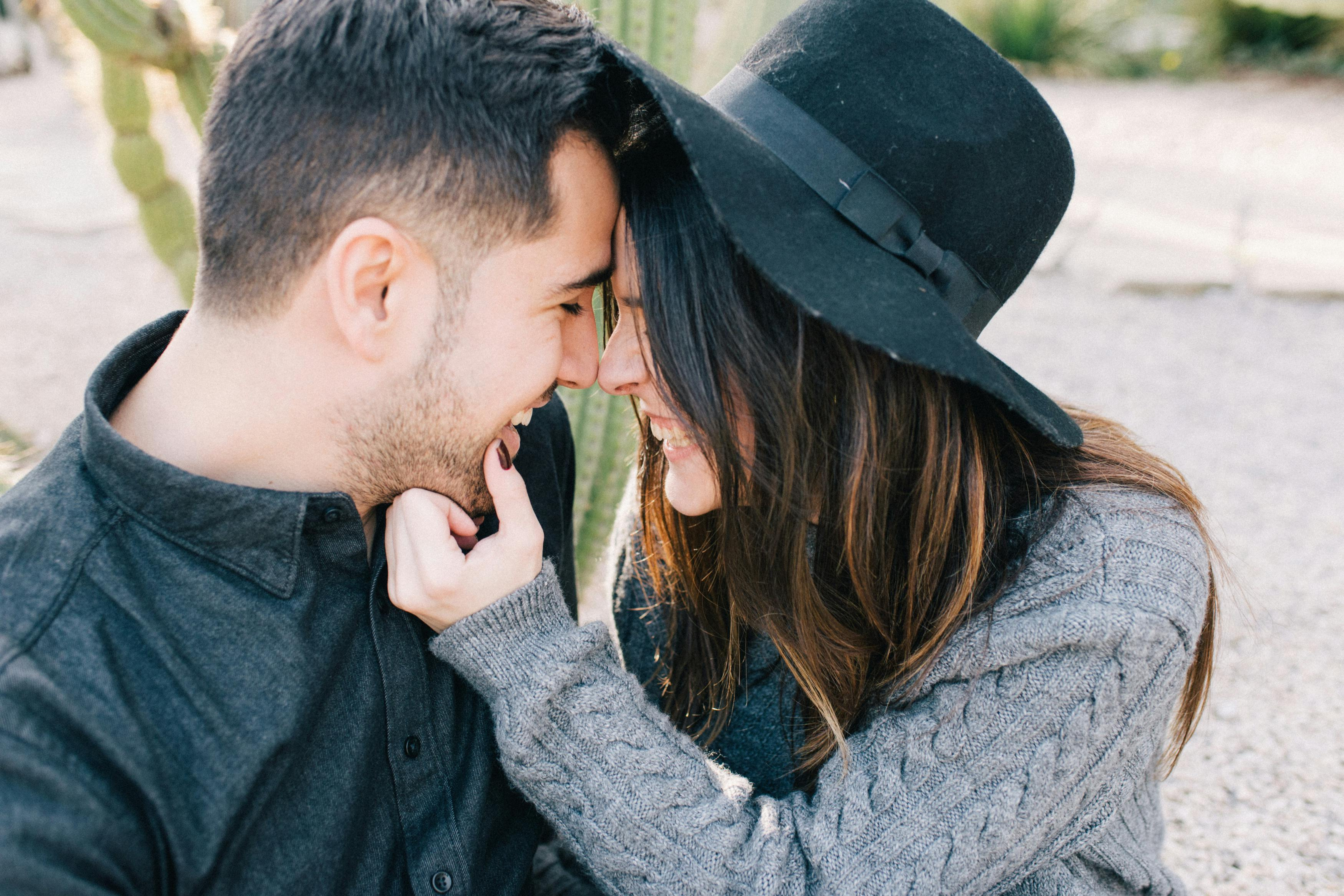 woman in black hat smiling and touch face of man in black shirt