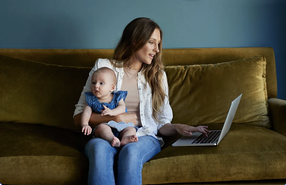 mother with baby on a couch with a laptop