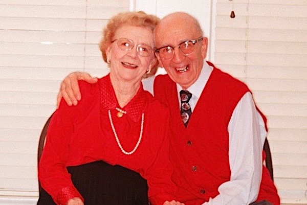 Senior man and woman dressed smartly in red sitting together and smiling