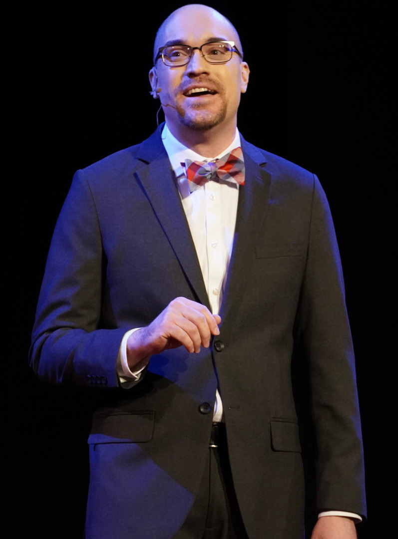 A photo of Matthew Courtney speaking on the TEDx stage. 
