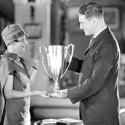 man awarding winners cup to woman