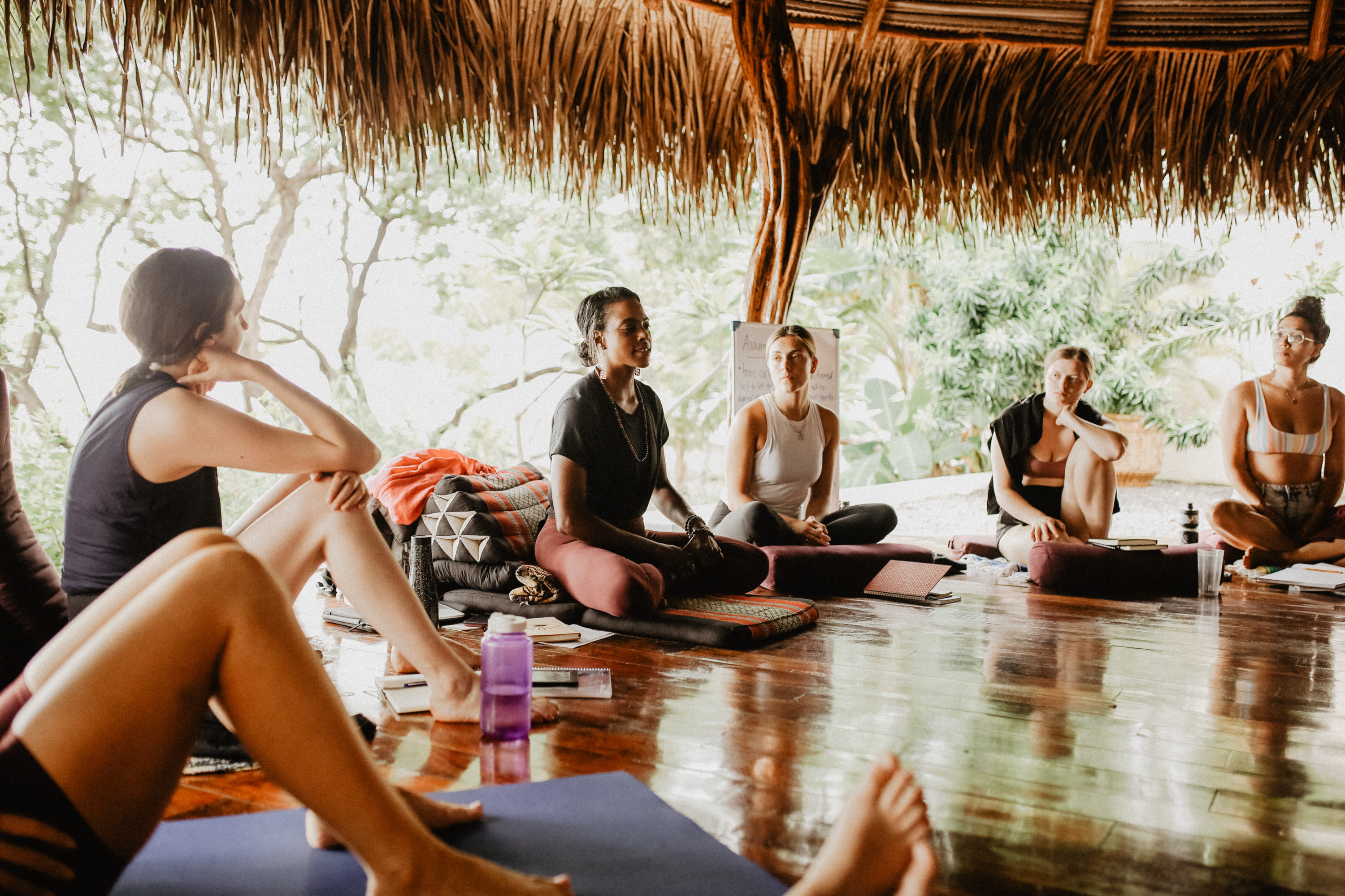 Michelle teaching a group of people who are seated on the groud