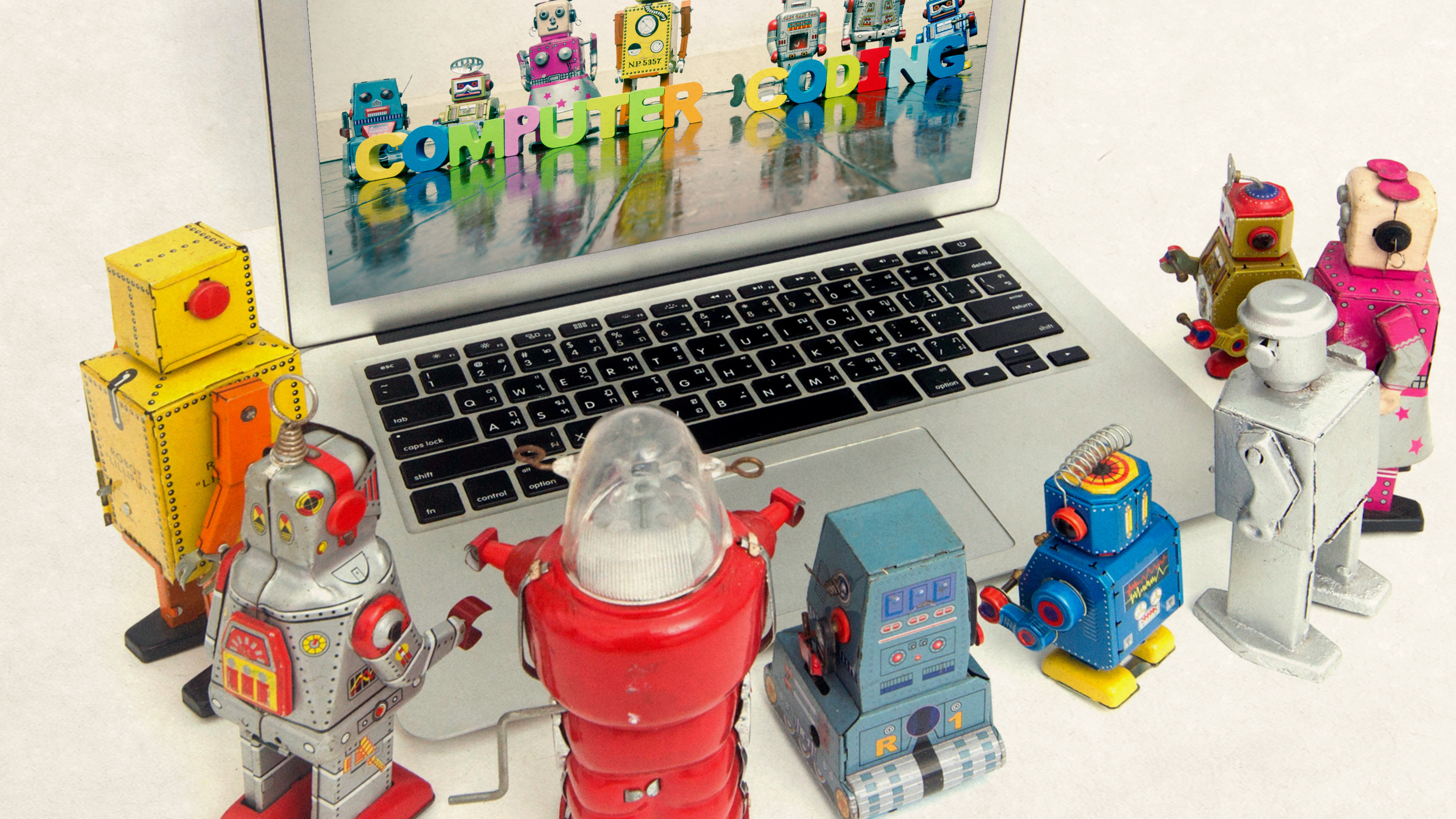 robots standing around laptop looking at robots