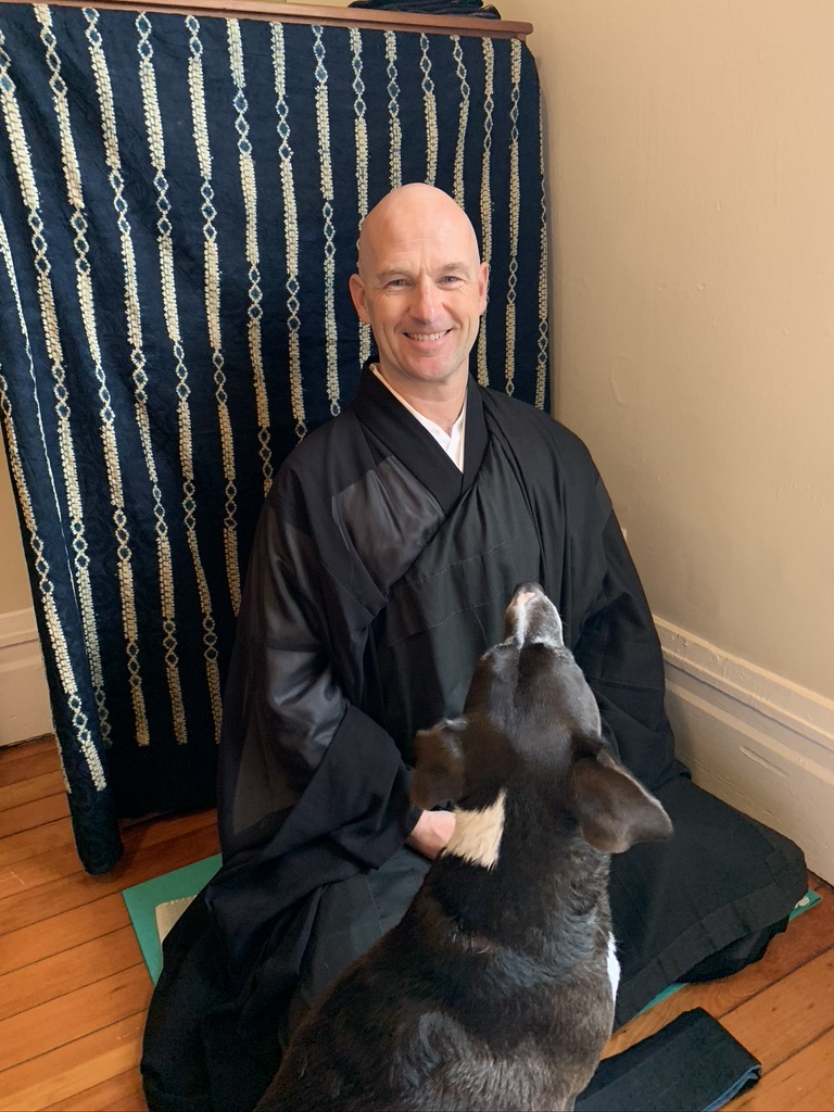 Shundo David Haye sitting in meditation posture with his dog, Collin.