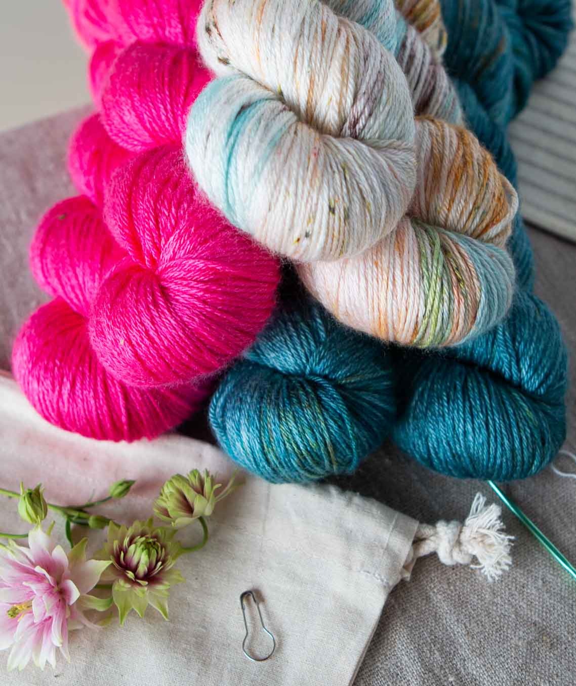 Pile of colourful yarn skeins on a cotton table cloth. 