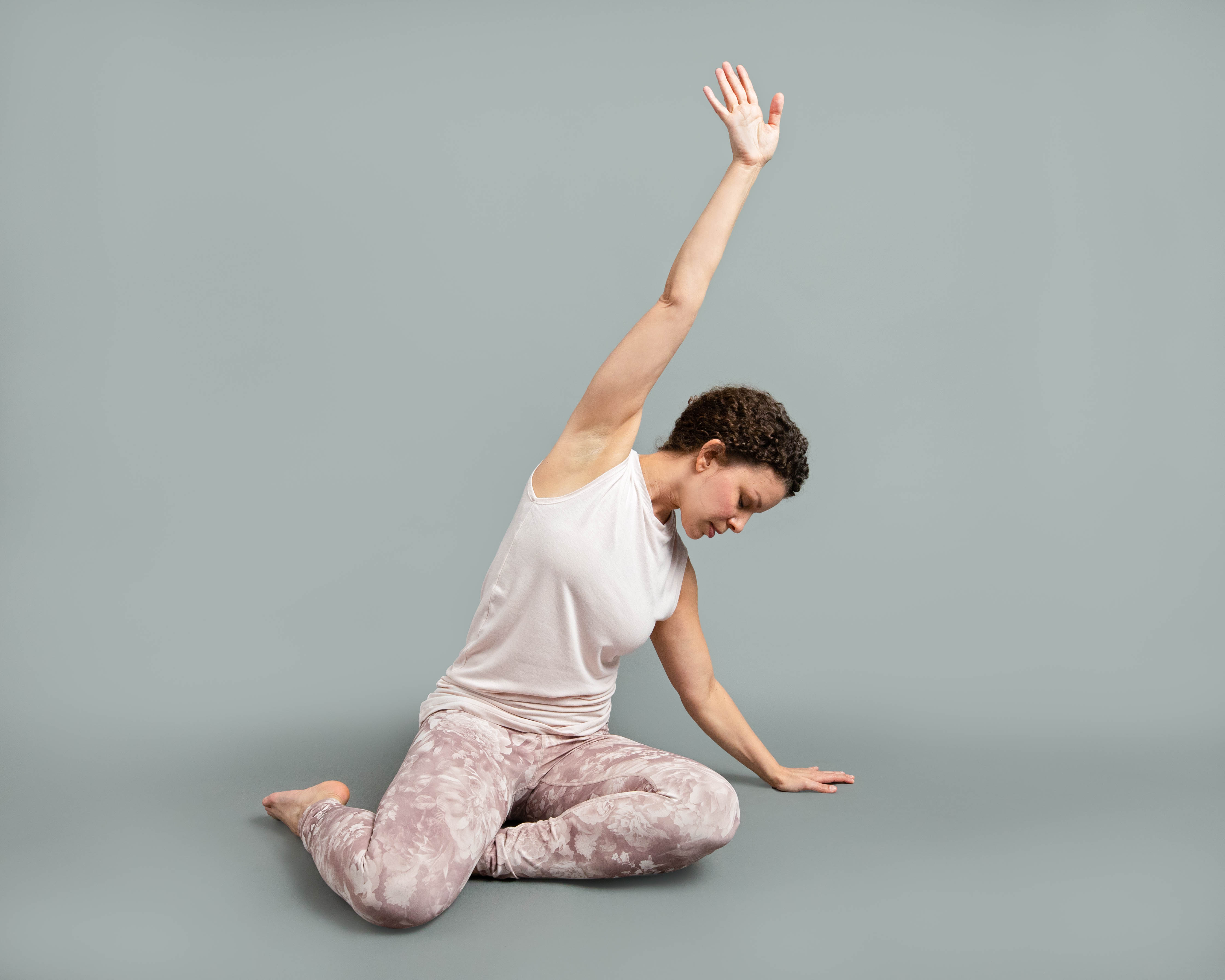 Woman in pink athletic clothing seated and stretching towards the side