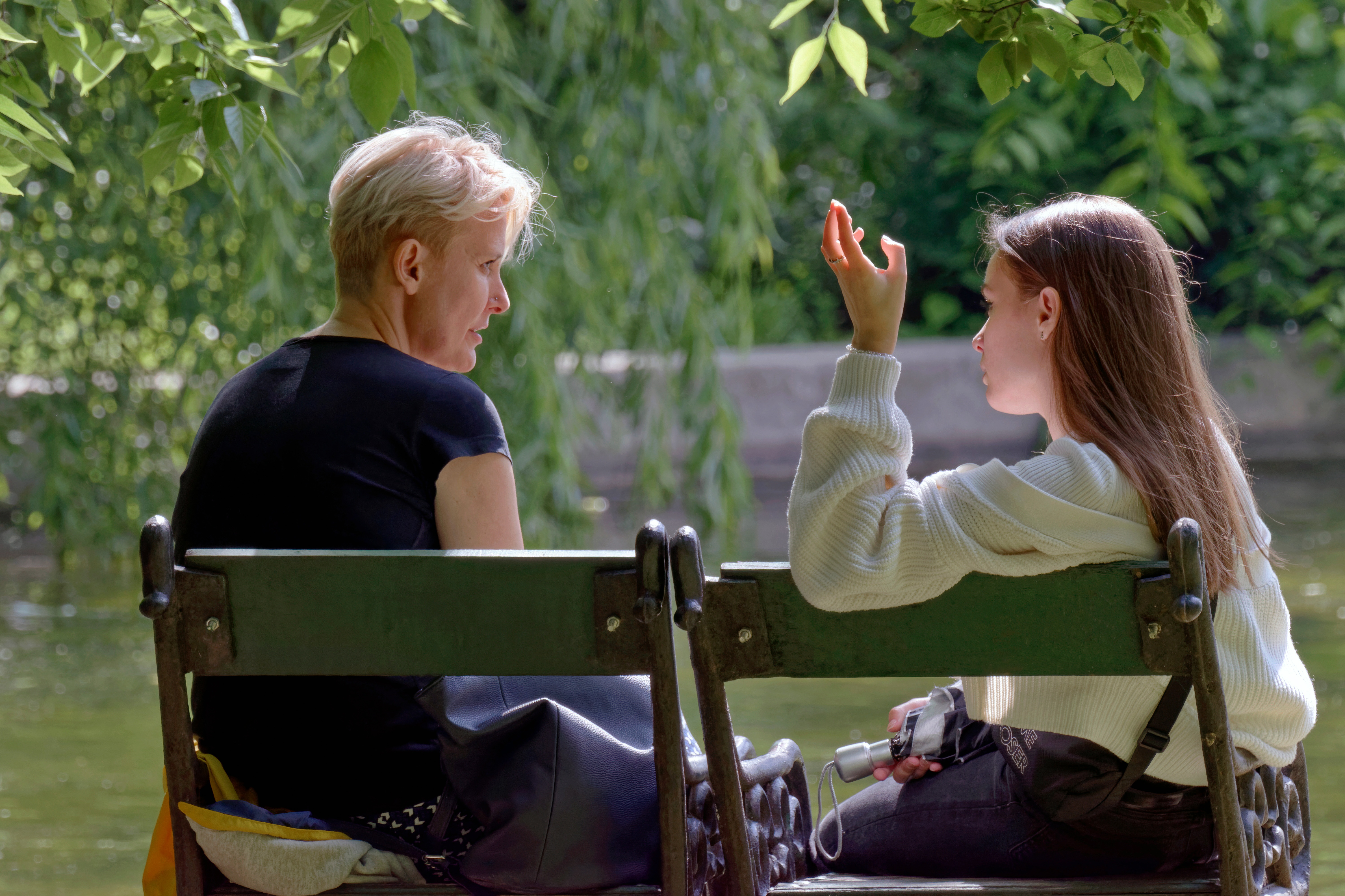 woman talking with a girl on a bench near a lake