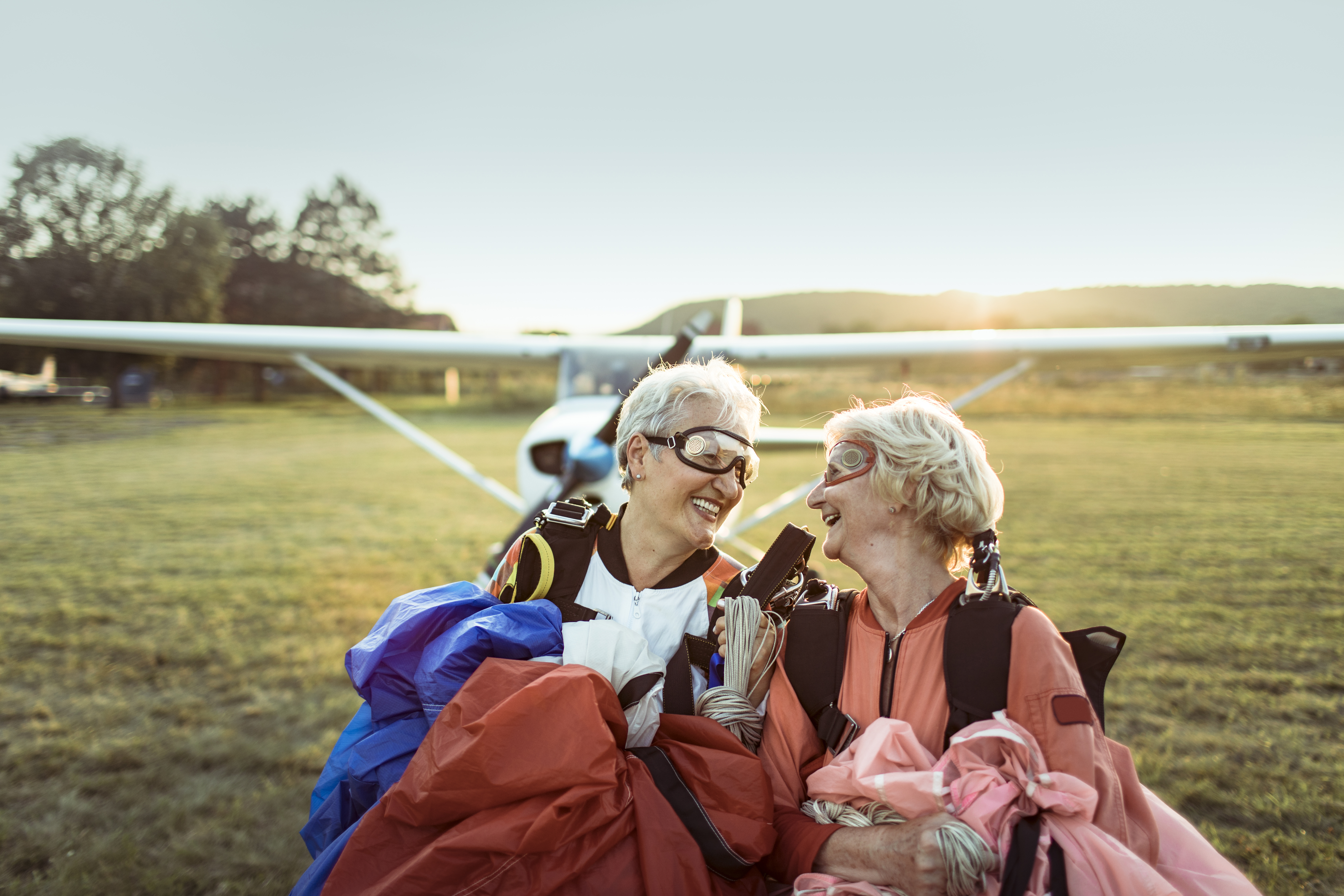 Retired friends in front of a plane, in a field