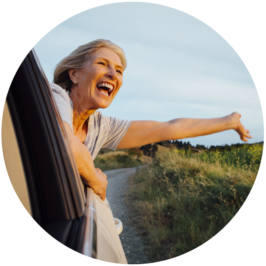 Person with their hand out of a car window and smile on their face