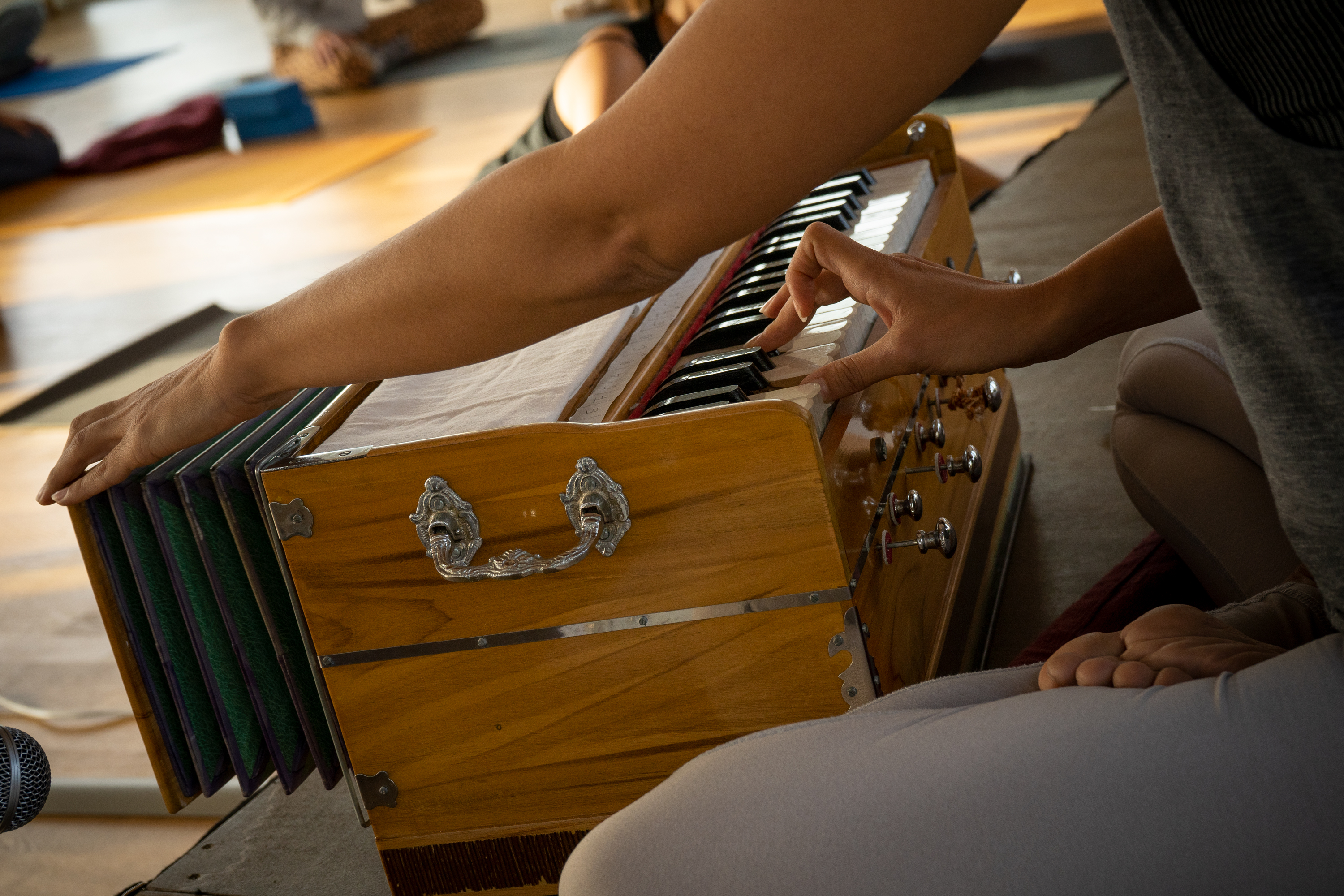 A person sitting in Padmasana (Lotus Pose) playing harmonium