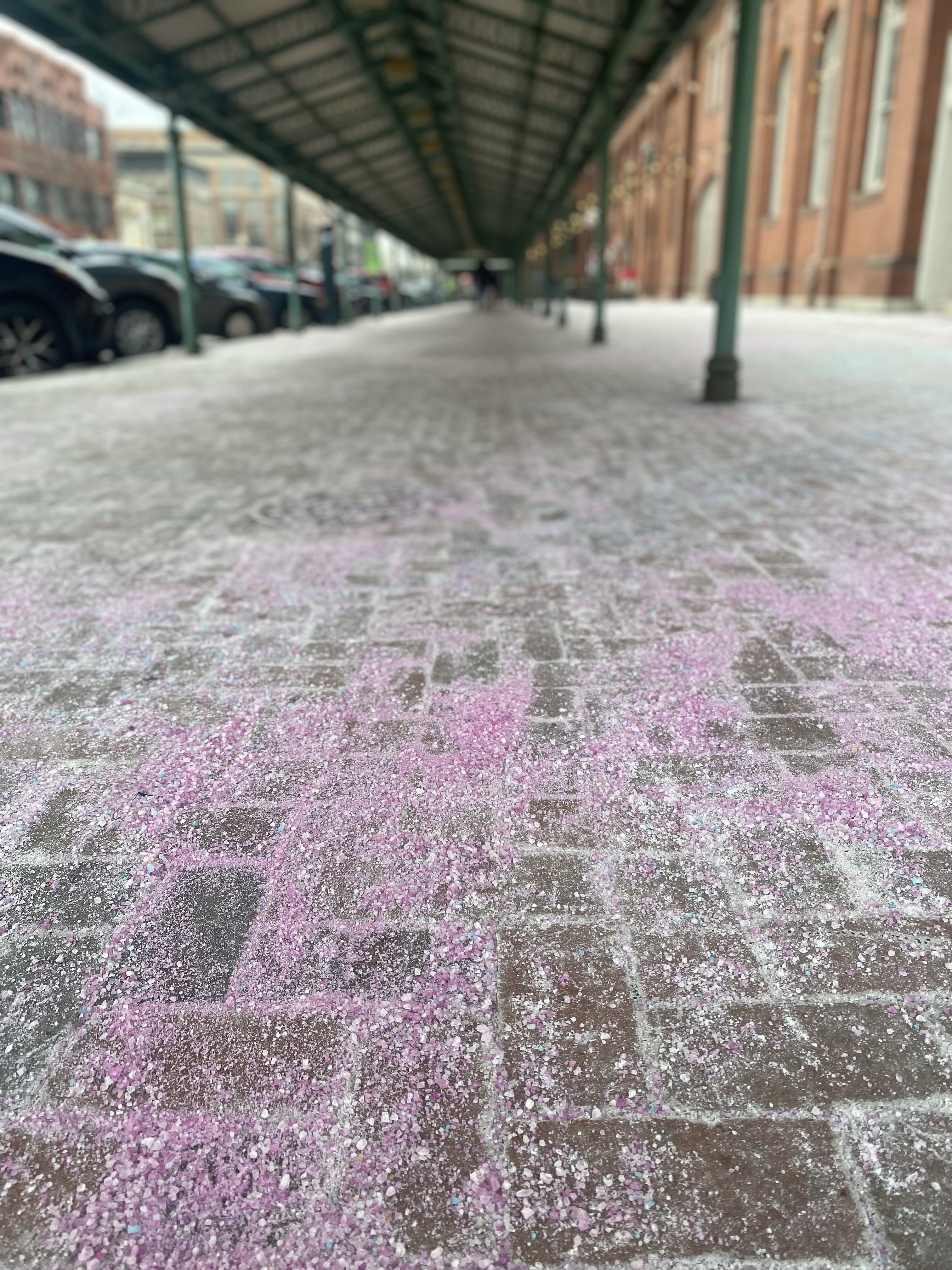 Pink salt is scattered over a brick sidewalk near a 19th century red brick building in Washington, DC