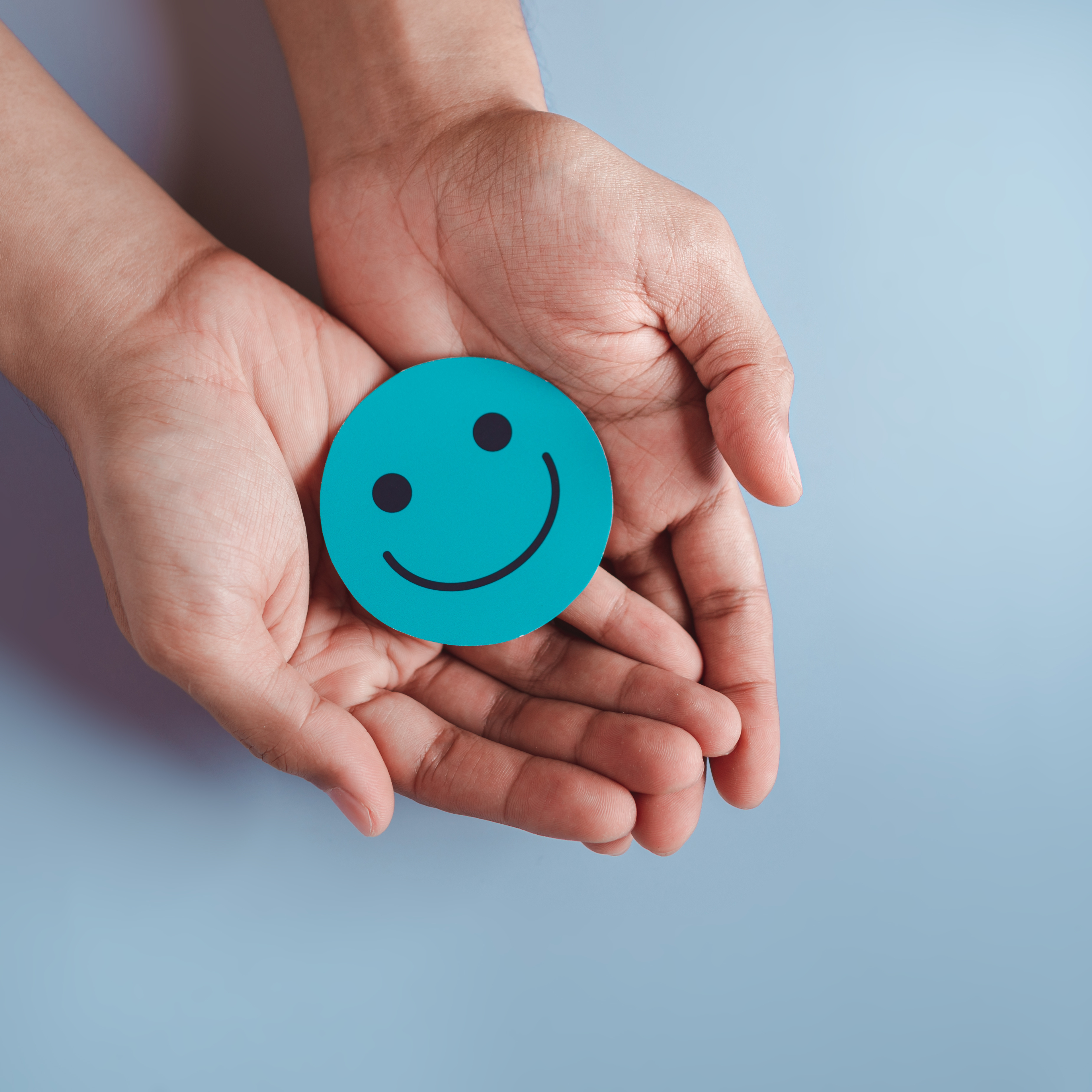 hands holding a blue smiley face