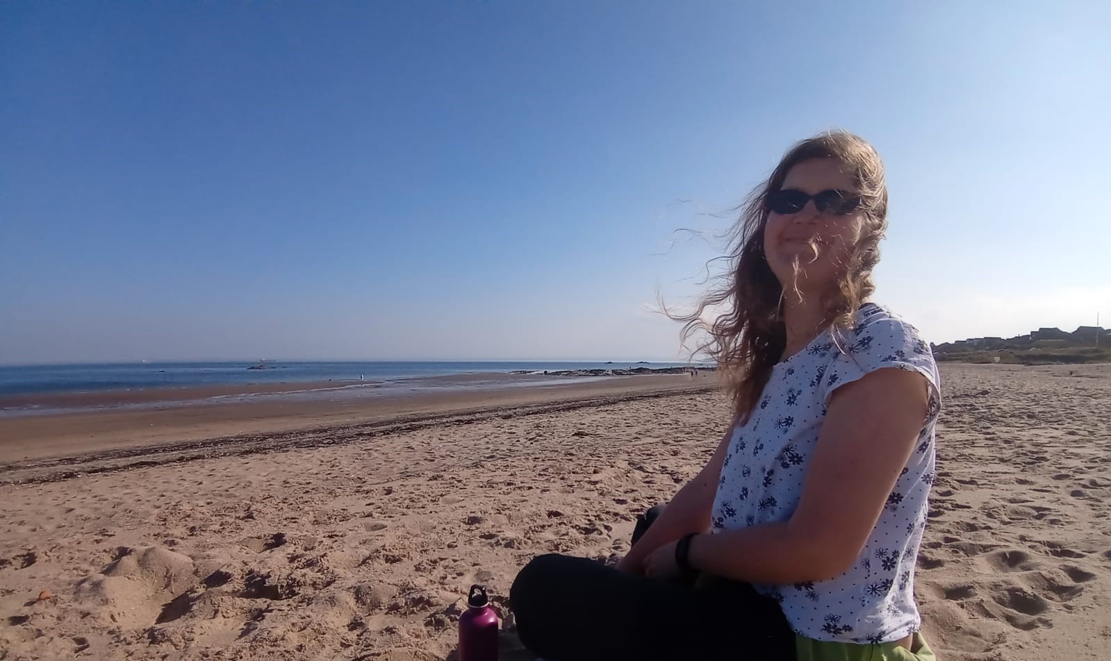 English Language Coach for non-native Teachers of English sitting on a beach in the sunshine