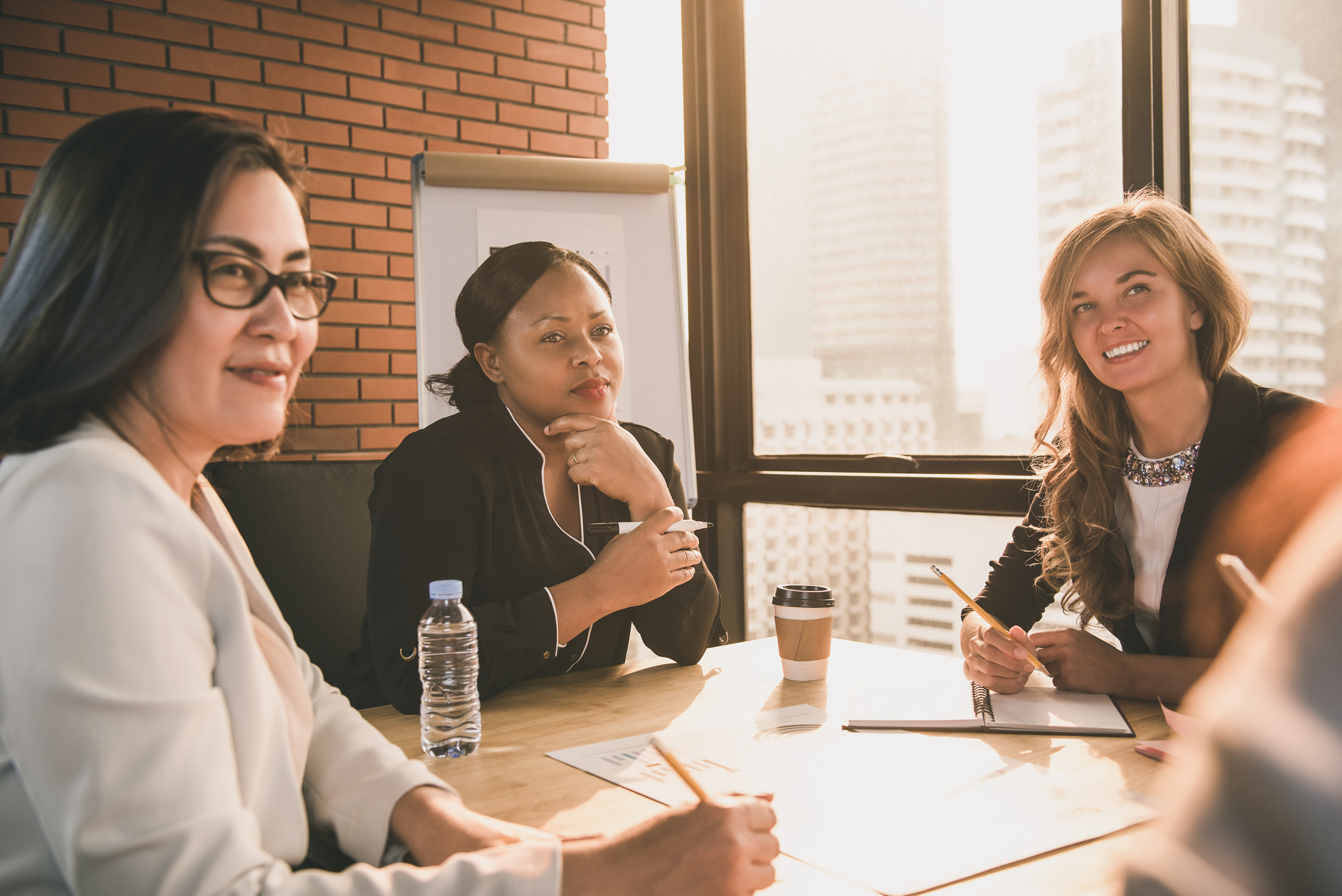 Three business ladies sitting around a table listening to a speaker