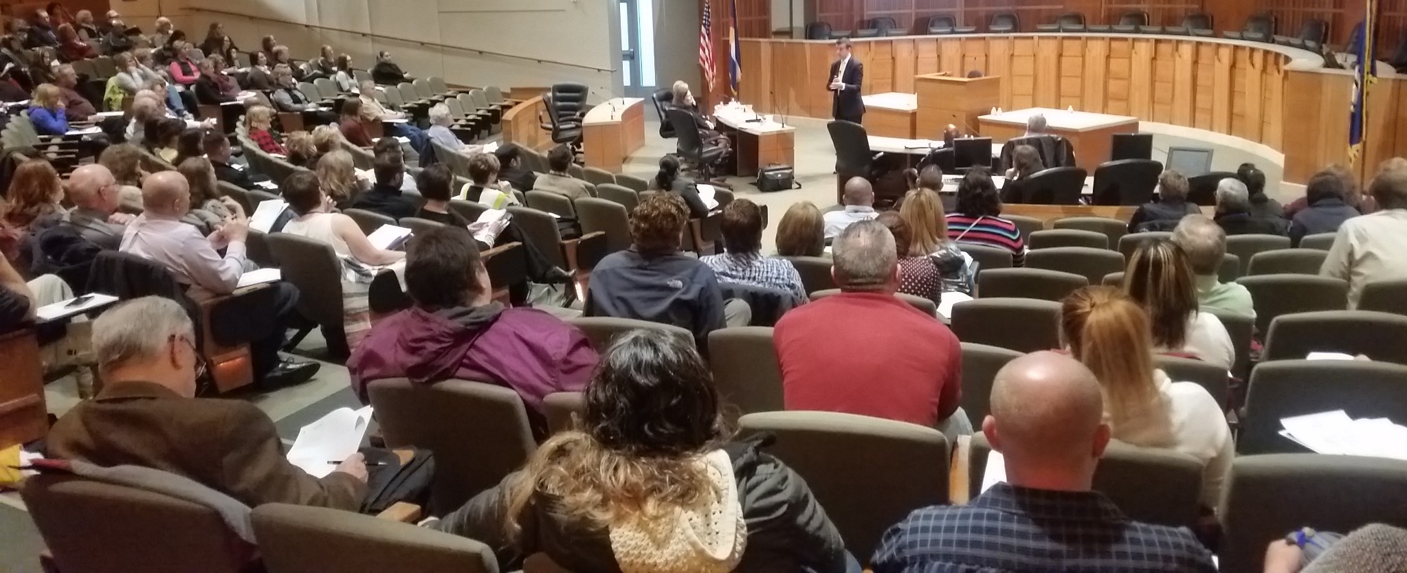 Group of people sitting in a room listening to a speaker