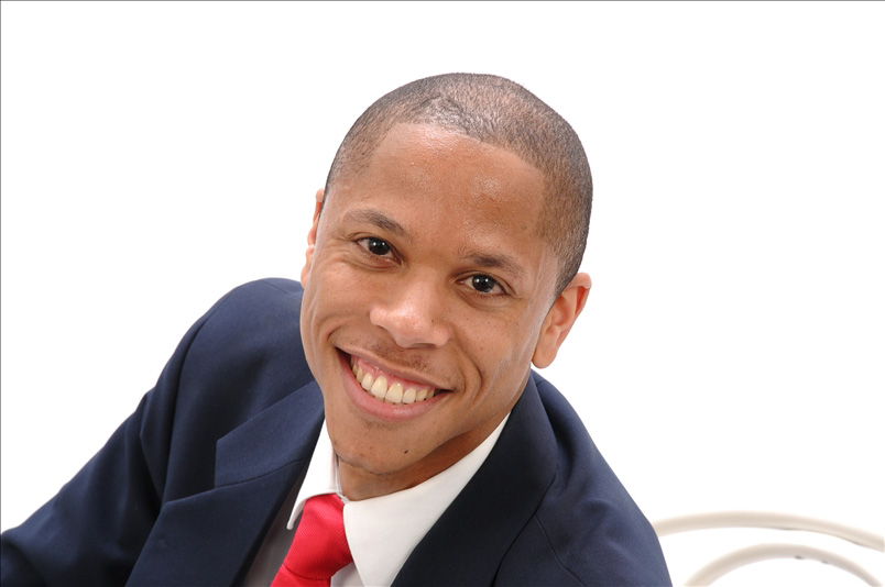 picture of Coach Dominique Edmond sitting in a chair, smiling