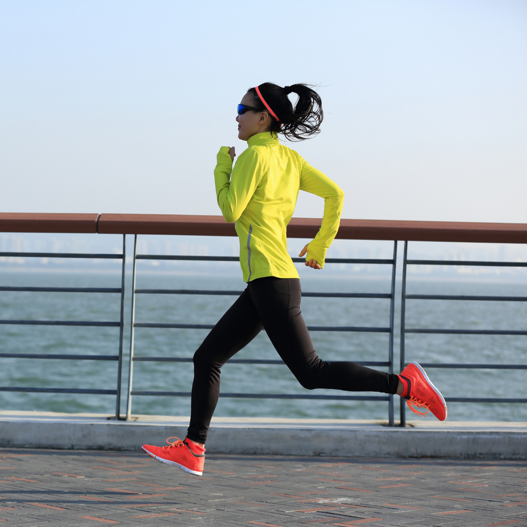 Woman running beside the ocean with intensity, which strengthens lower-body strength and prevents ACL injury.