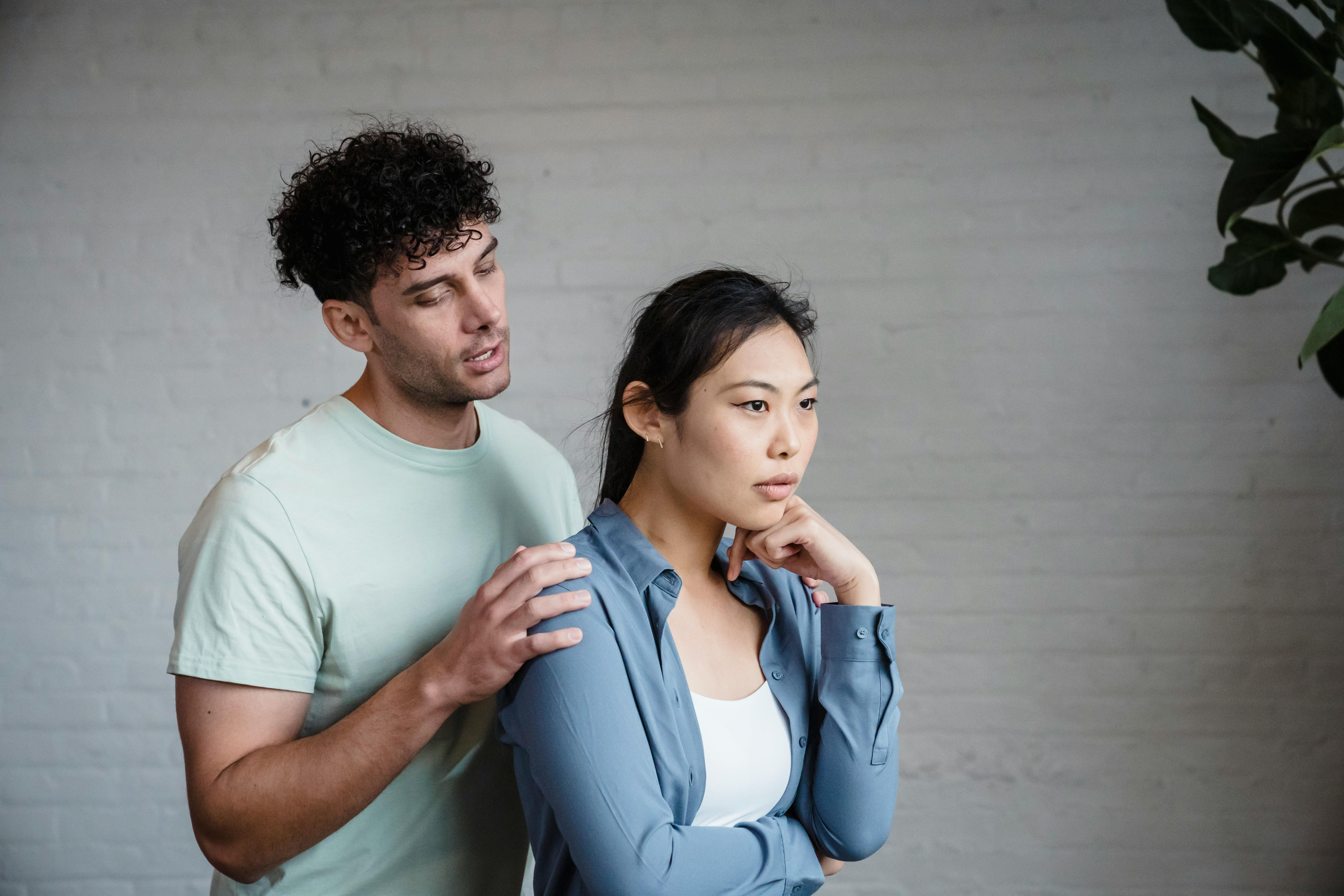 Asian woman in blue shirt standing in front of man with light green shirt