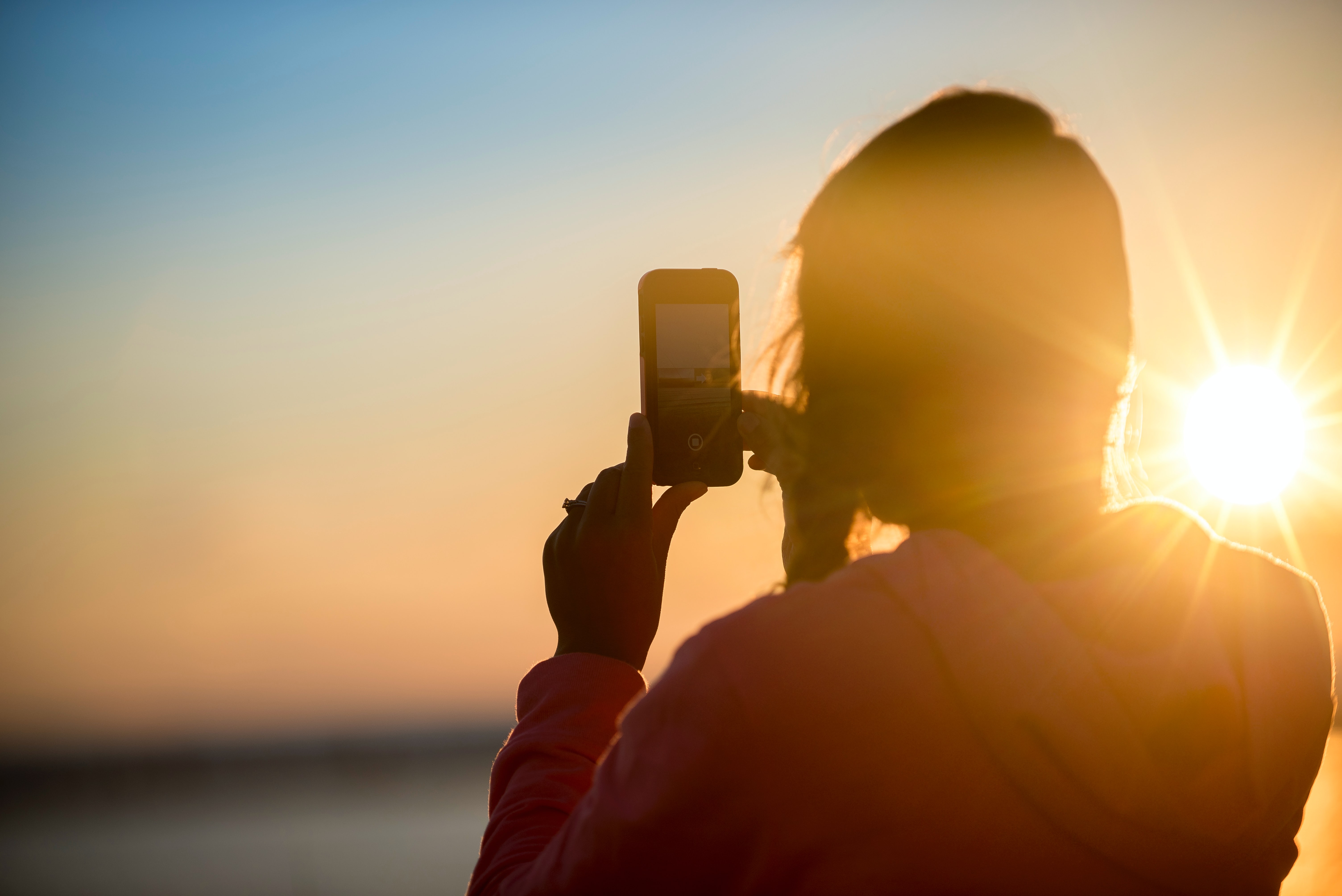 Photo d&#39;une personne tenant un smartphone pour prendre une photo à contre-jour