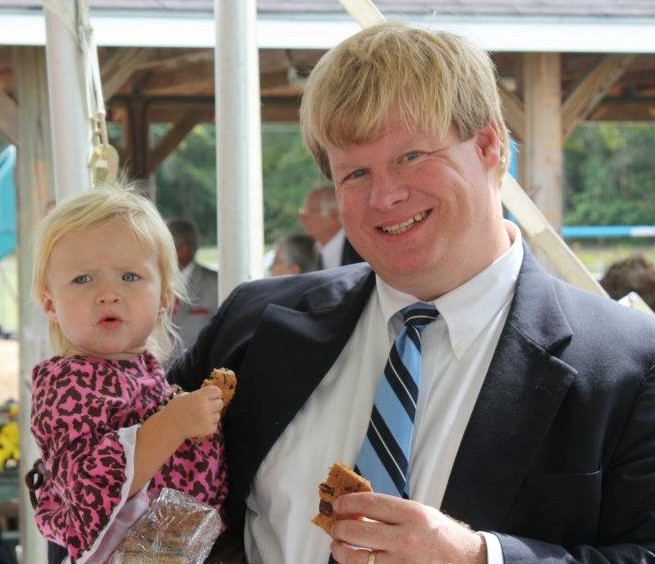 Man holding a child and a cookie.