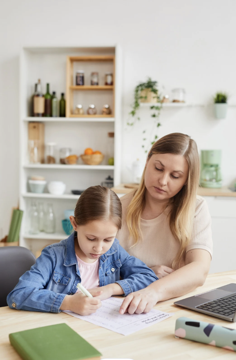 A young mother helps her daughter with homework.