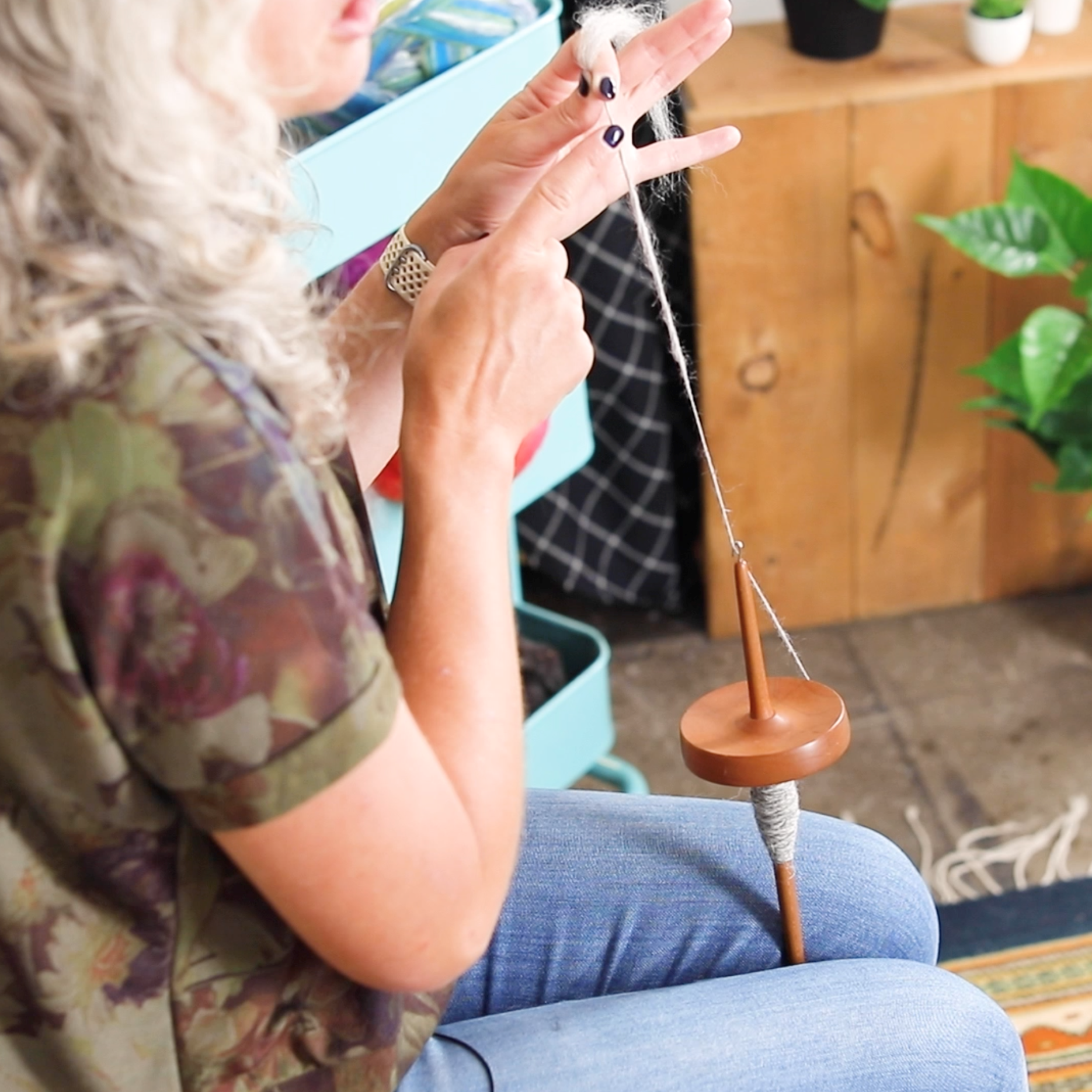 Jaime holding spun yarn attached to a drop spindle