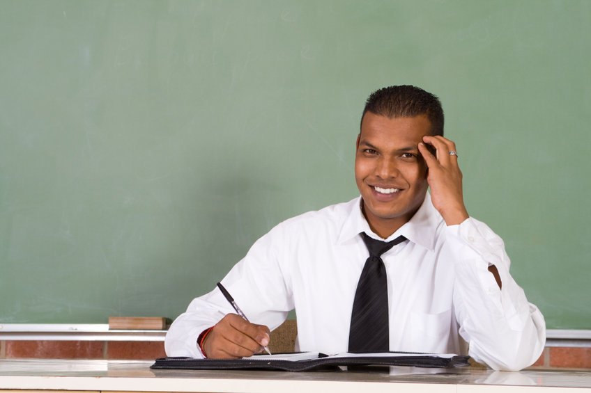 Principal sitting at desk writing with a pen