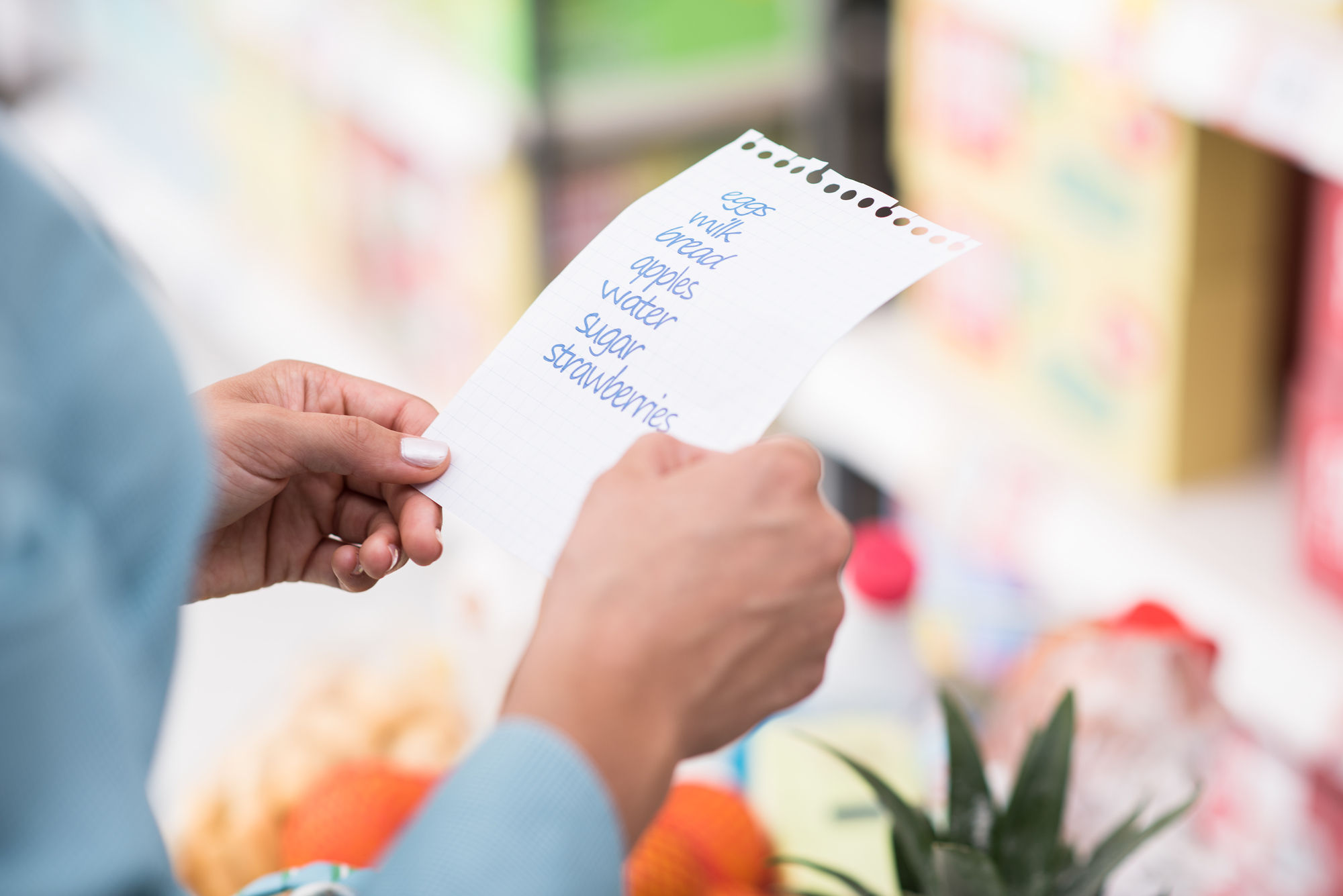 womans hands holding shopping list