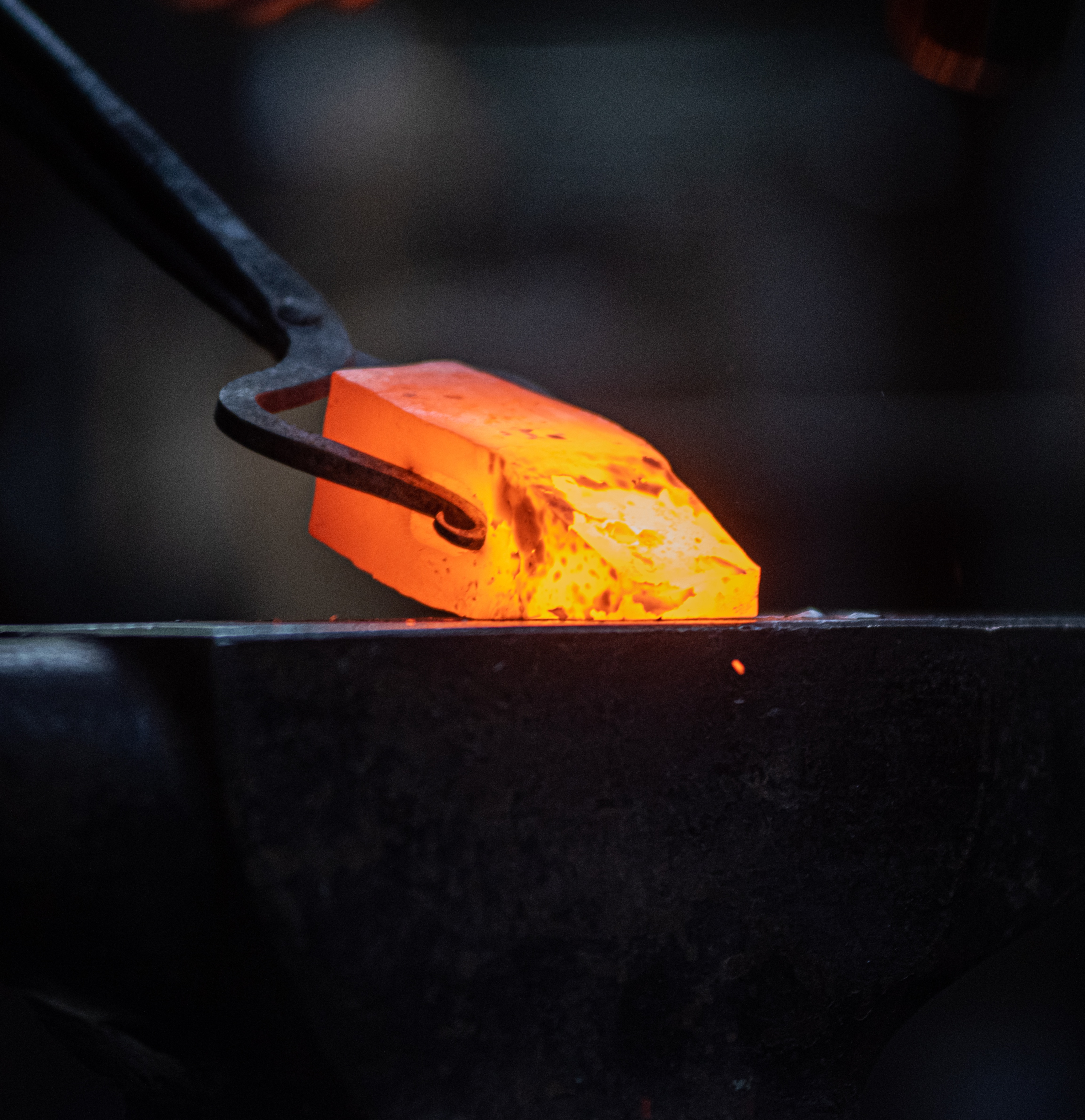 Blacksmith holding a piece of heated metal in tongs