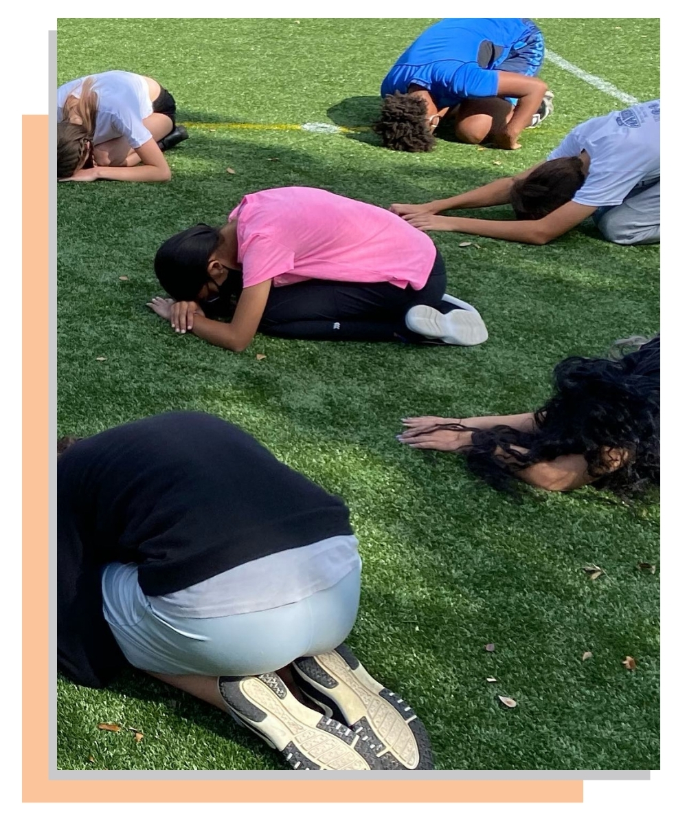 Students in Balasana on the grass