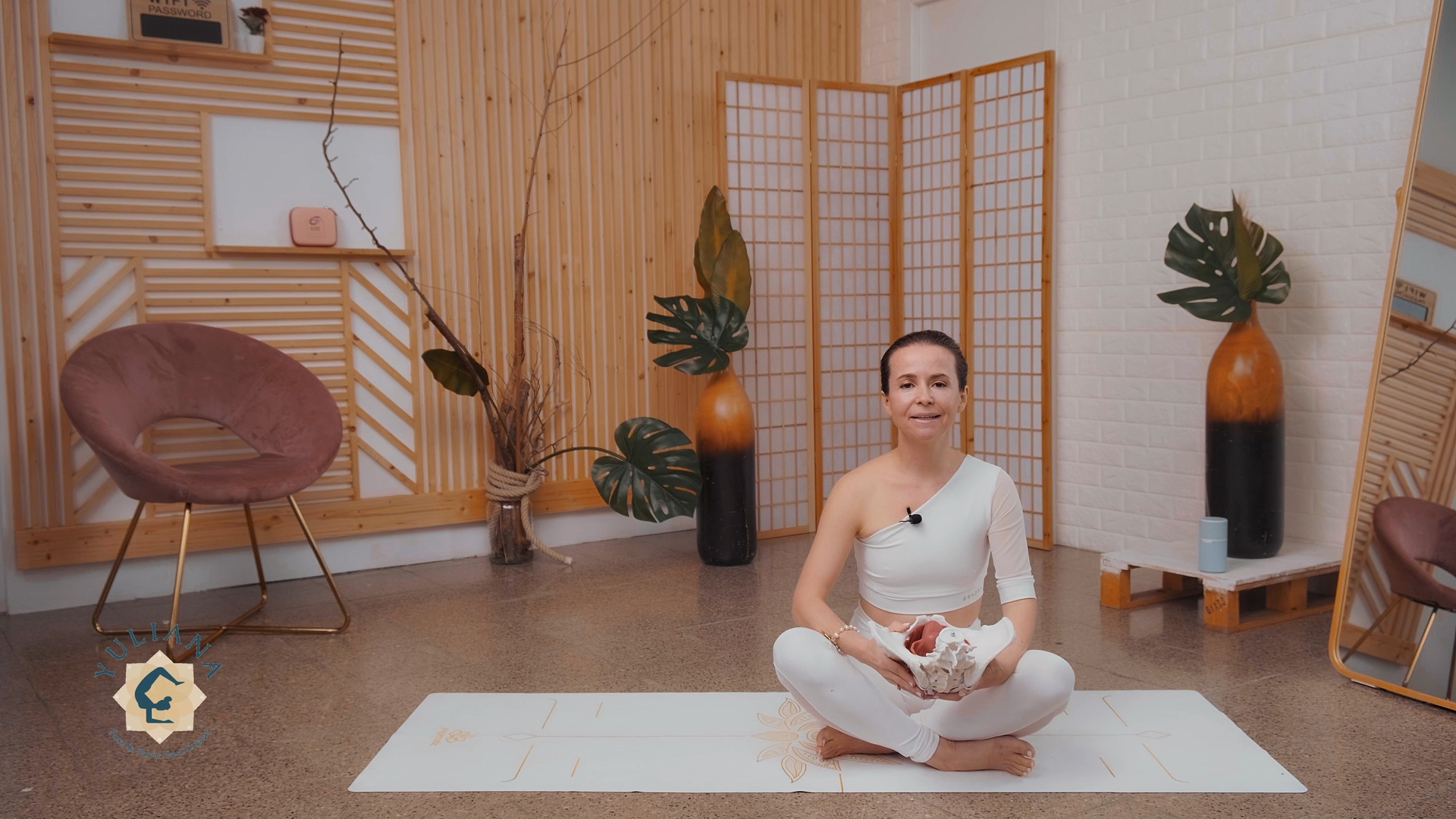 woman in a workout yoga studio is holding a pelvic floor model in her hands teaching a class on pelvic floor health