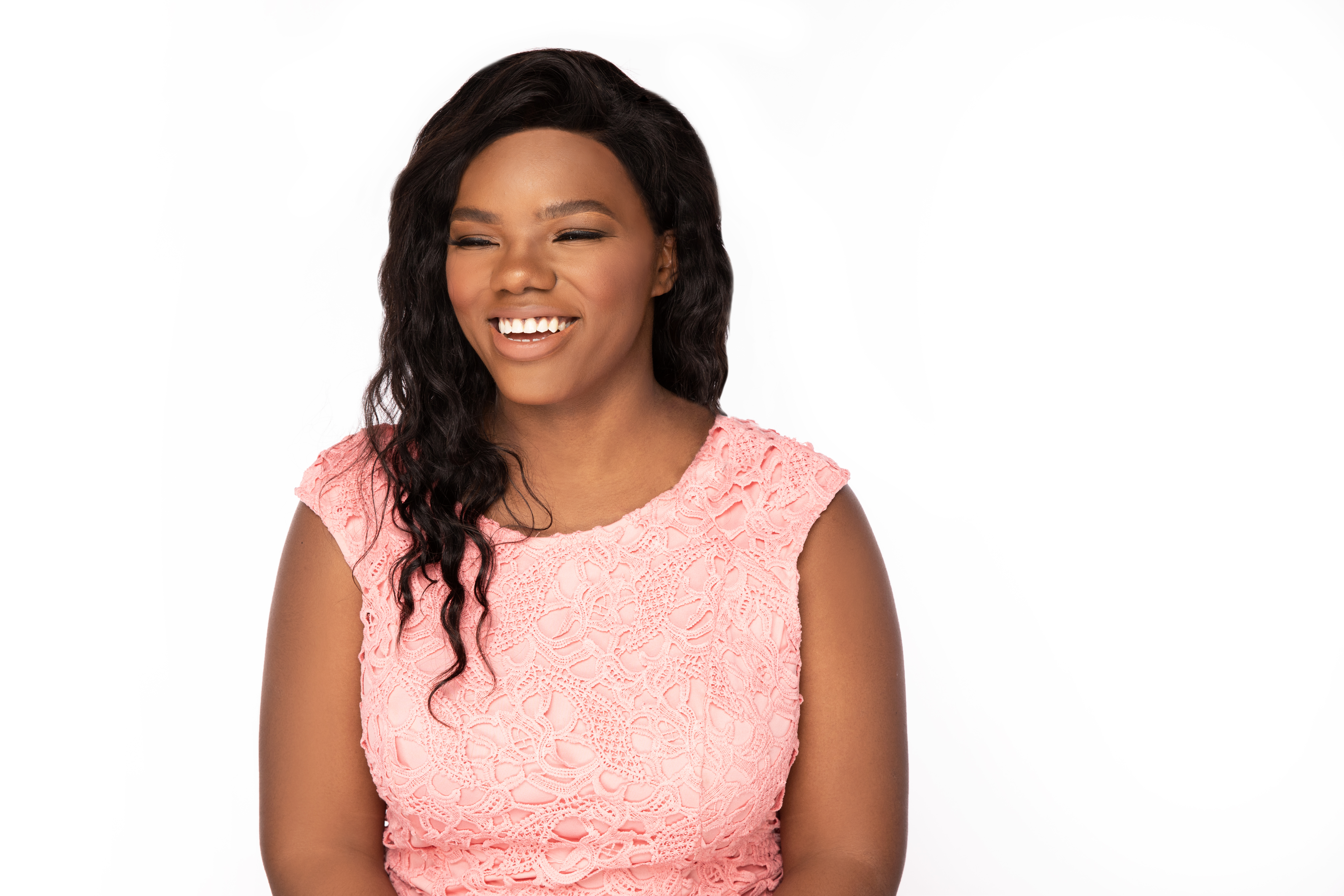 Image of African American women with lightly curly hair. Woman is smiling and wearing a pink dressy top 